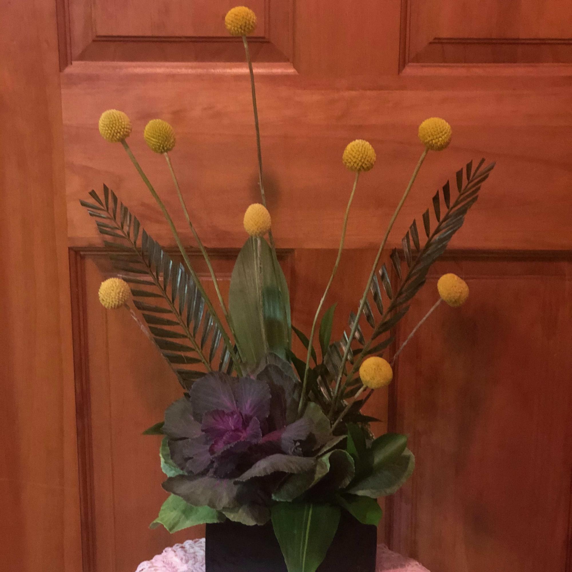 Modern floral arrangement with yellow globe blooms in a black square vase