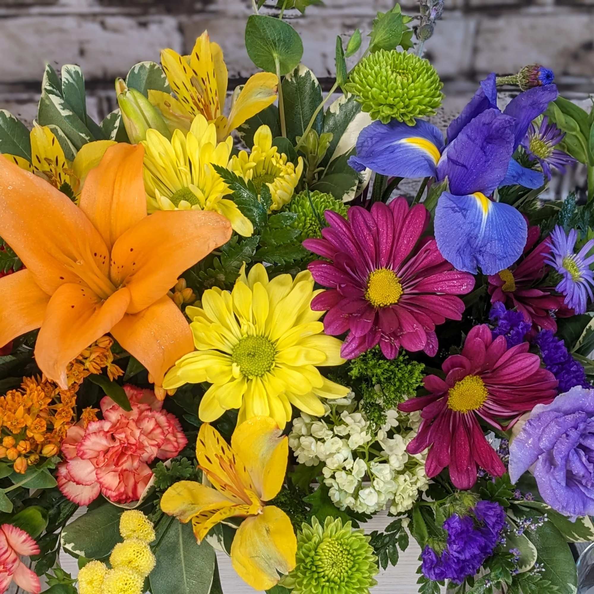 Mixed bouquet with orange lily, red rose, yellow daisies, and purple blooms
