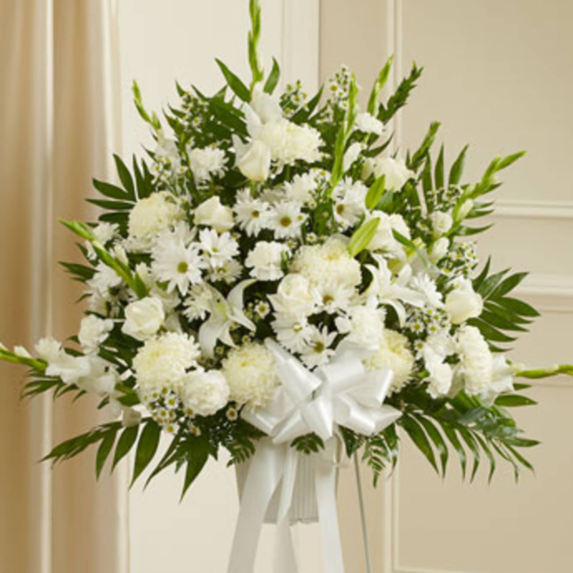 White floral standing spray with a ribbon on a white easel