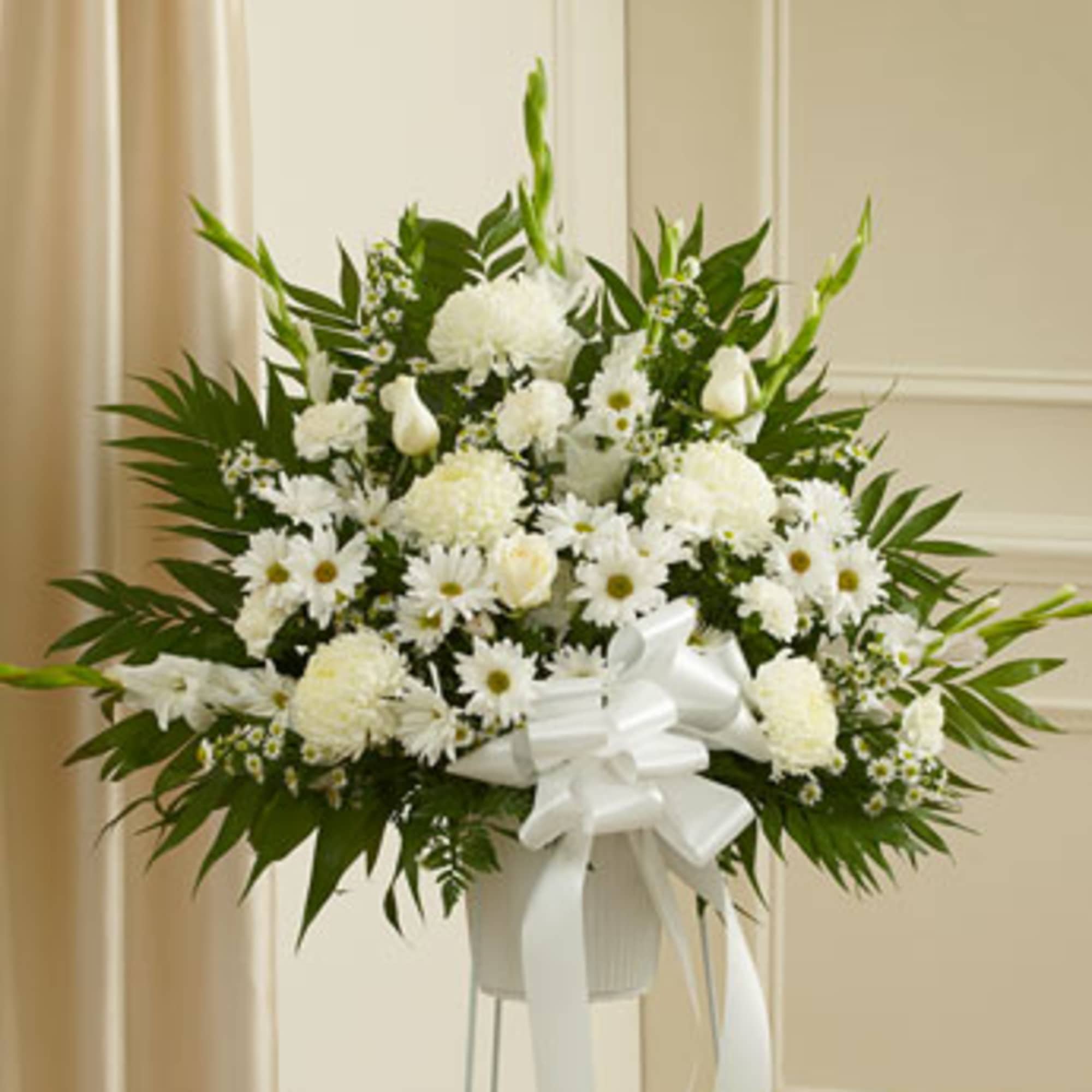 White floral standing arrangement with a ribbon on a pedestal