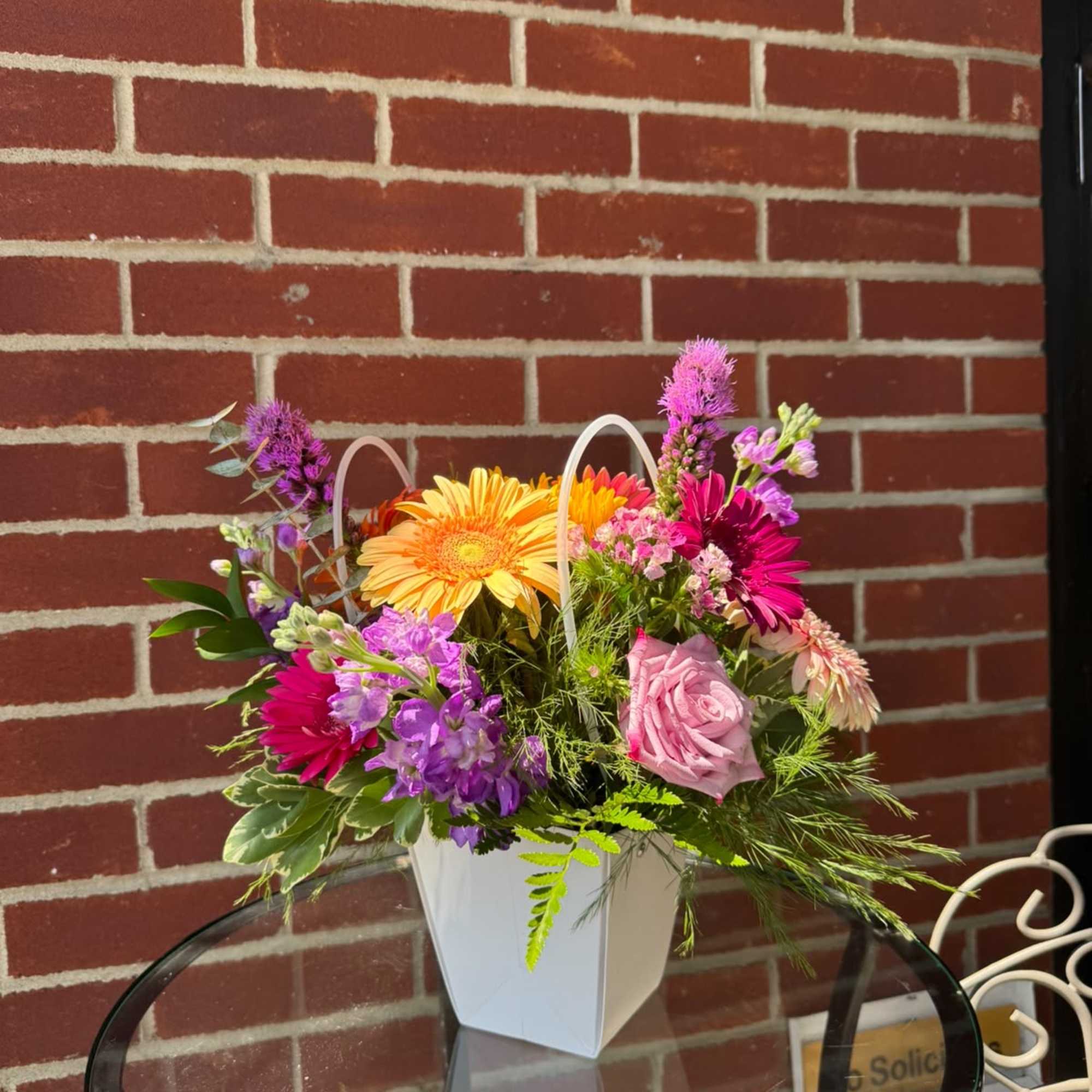 Colorful mixed flower arrangement in a white handled container