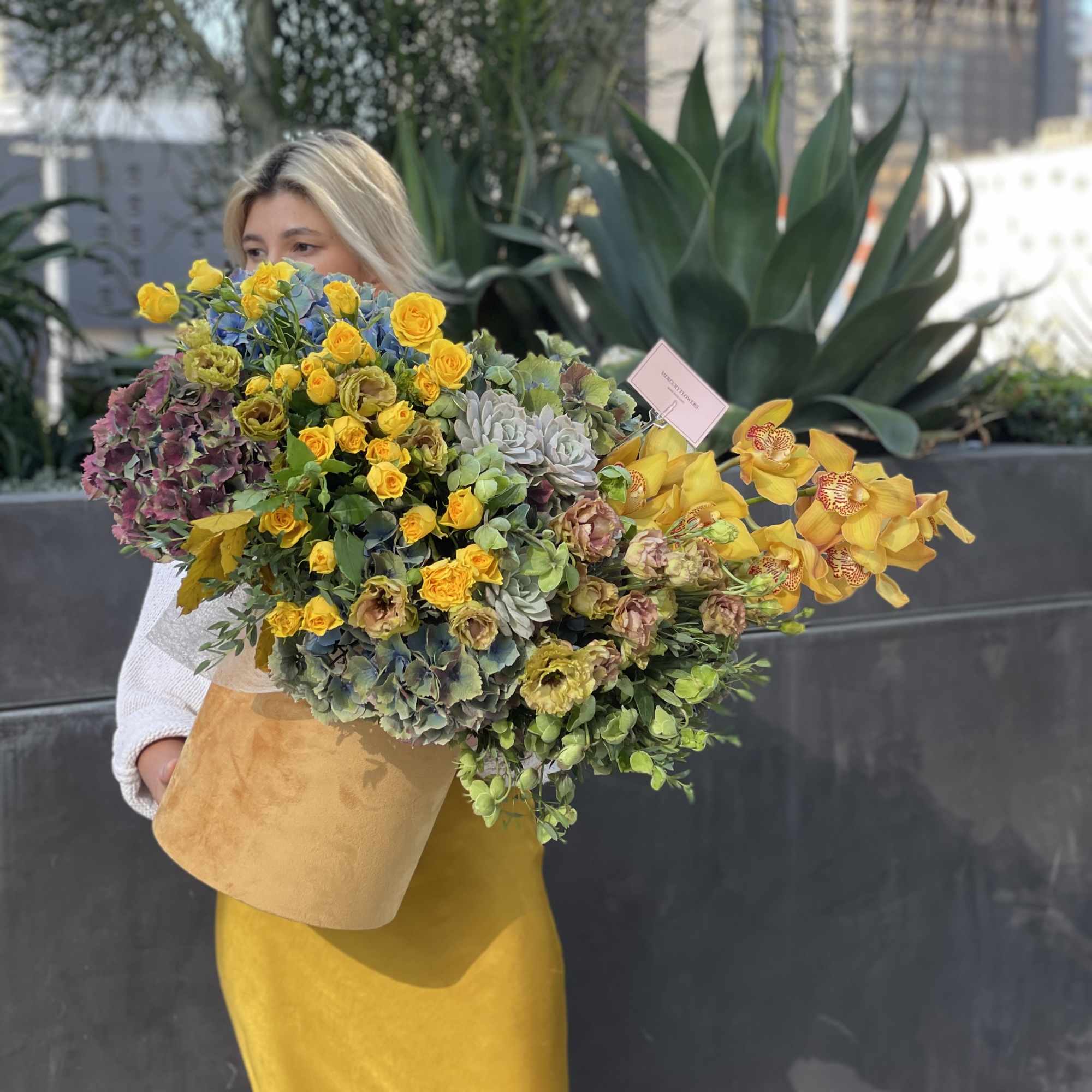 Large bouquet of yellow roses, orchids, and hydrangeas in a tan wrap