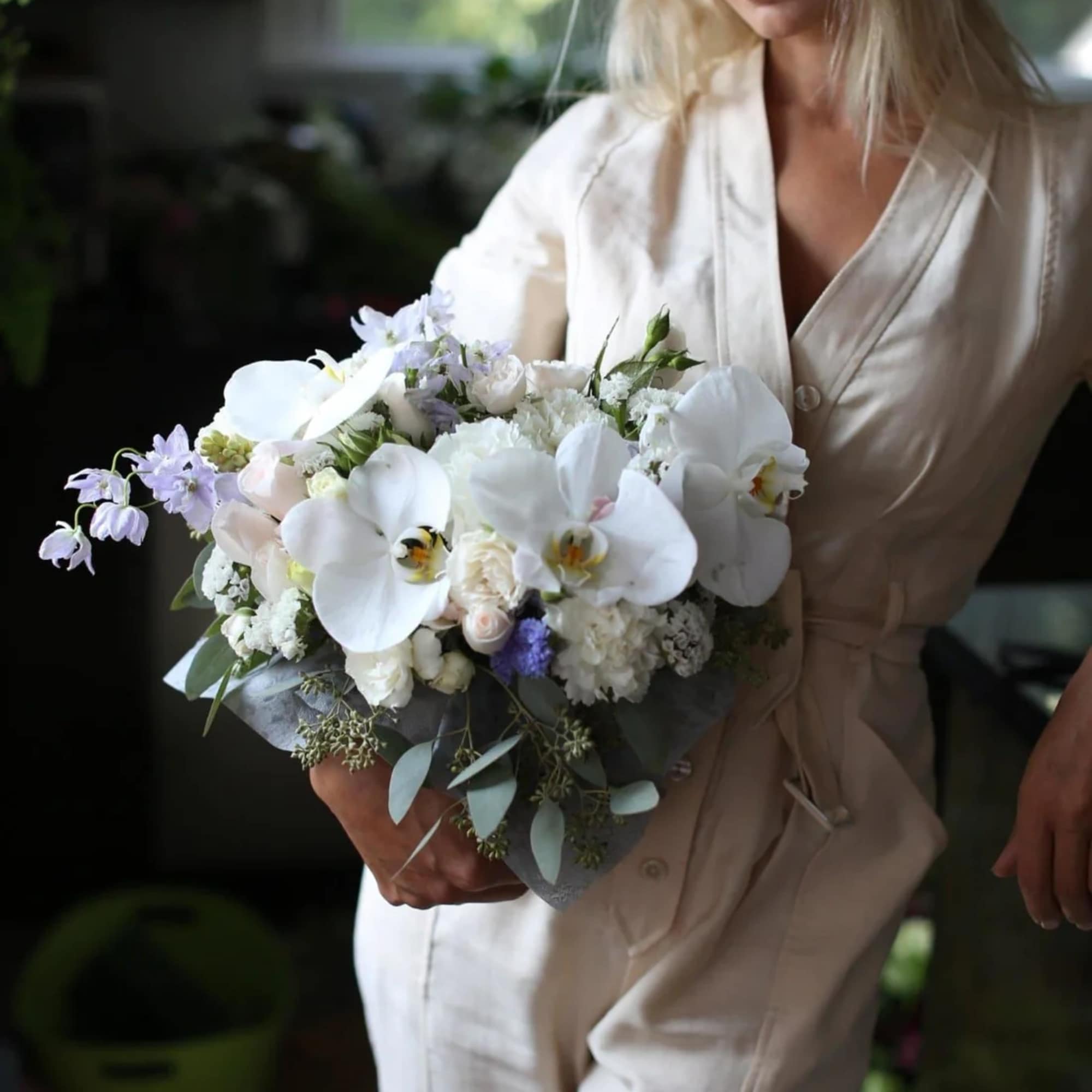 Woman holding a white and lavender bridal bouquet with orchids and roses
