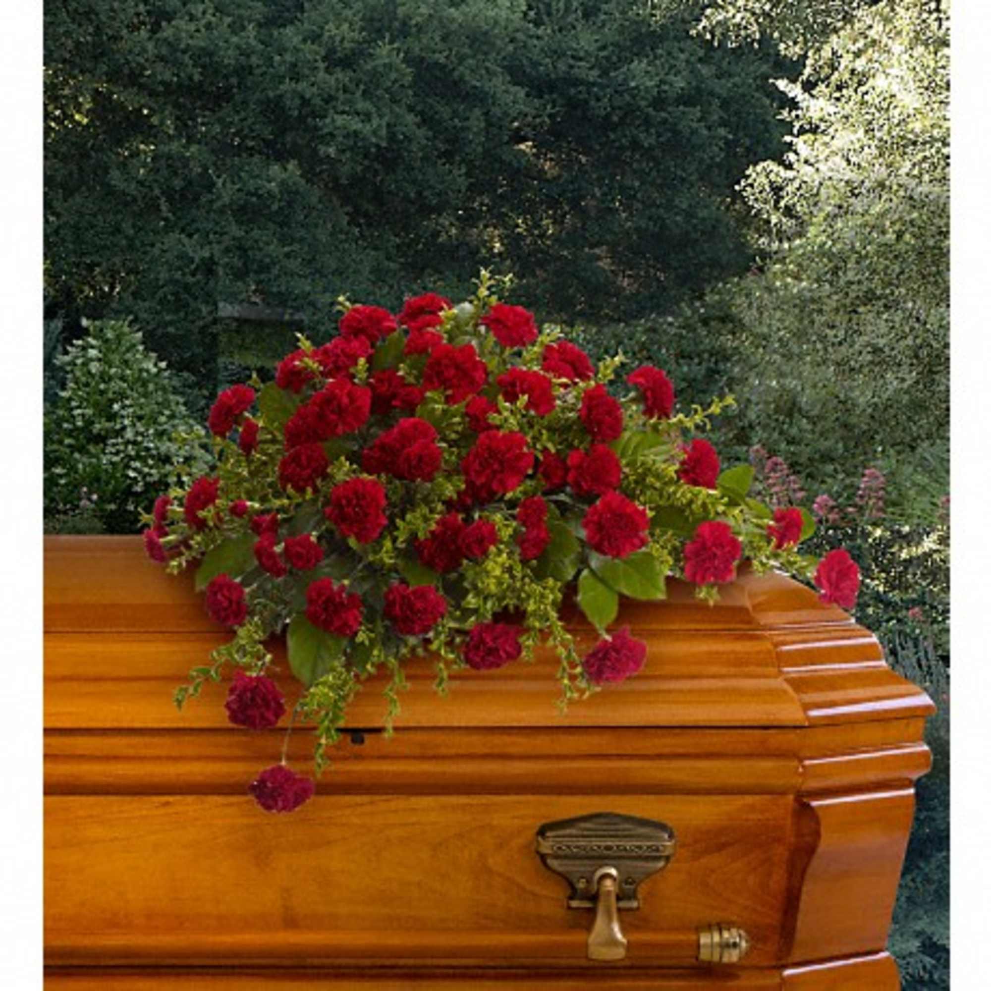 Red carnation casket spray on a wooden coffin