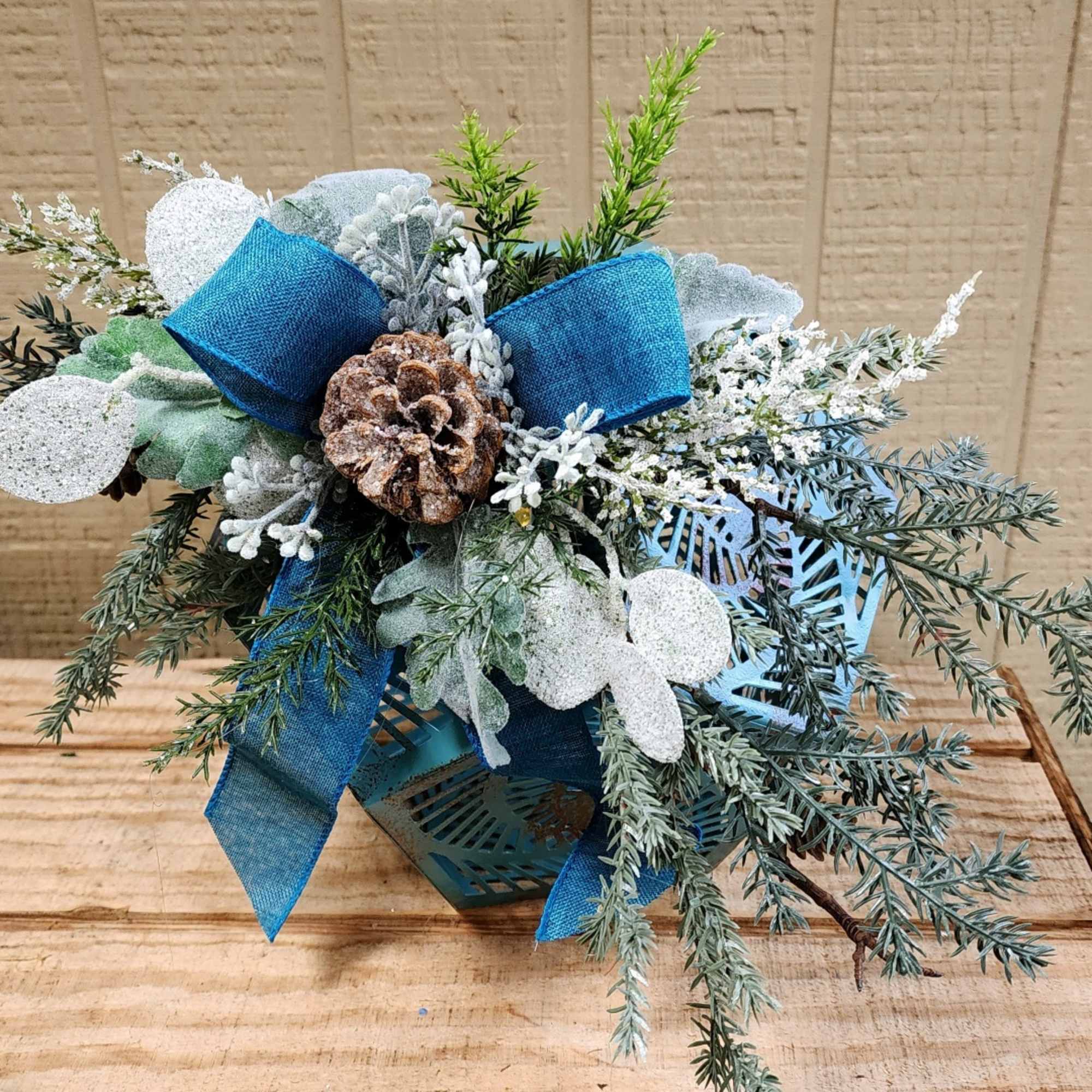 Blue ribbon arrangement with frosted pinecones and evergreen sprigs