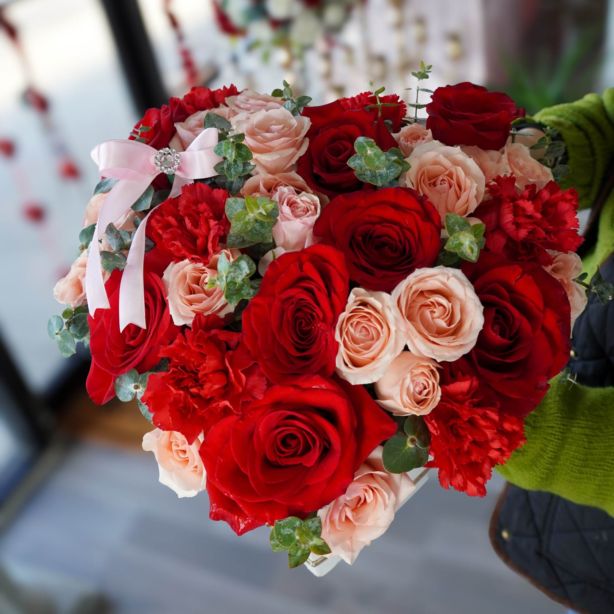This romantic heart-shaped arrangement features red and pink roses accented with lush