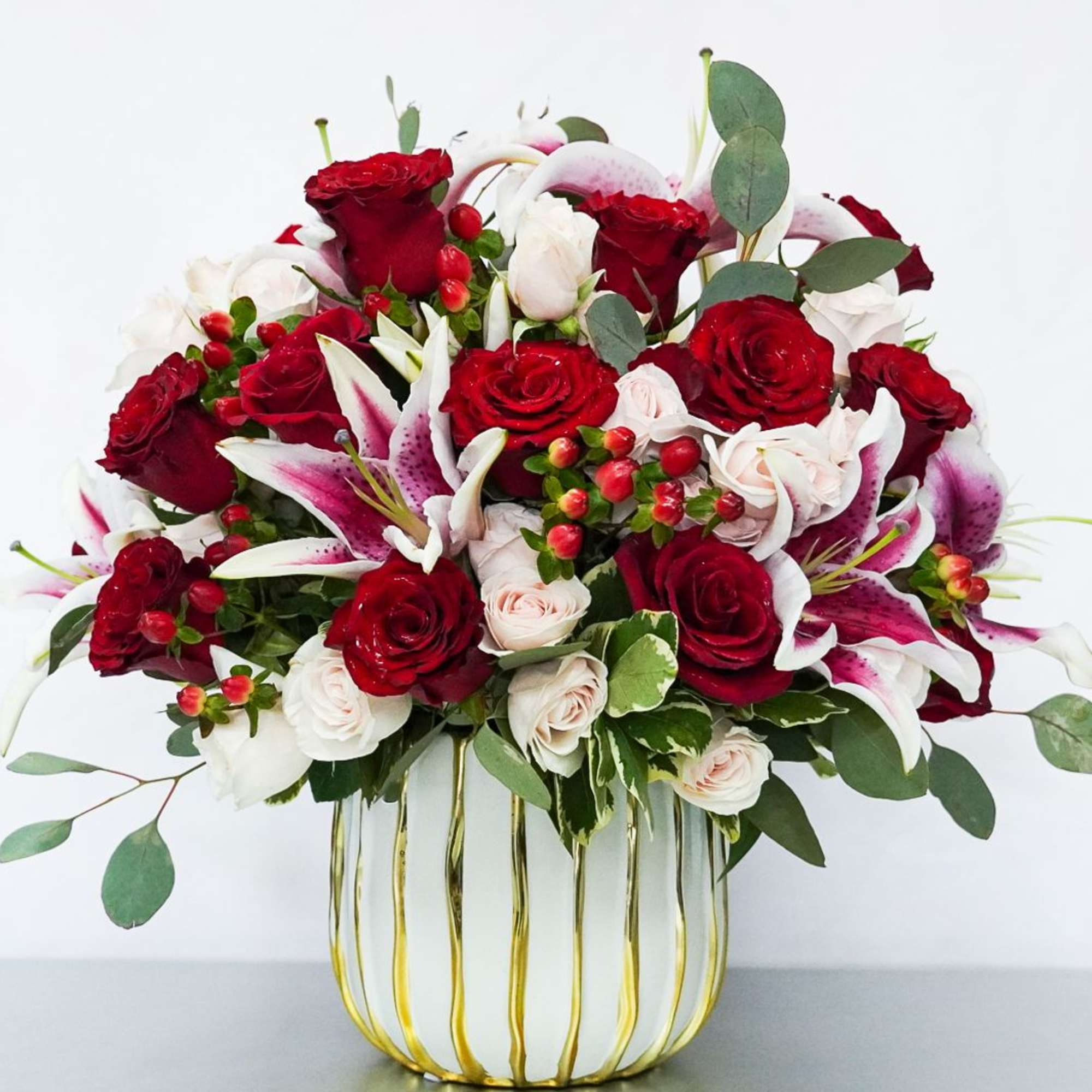 Red and white rose bouquet with lilies in a gold wire vase
