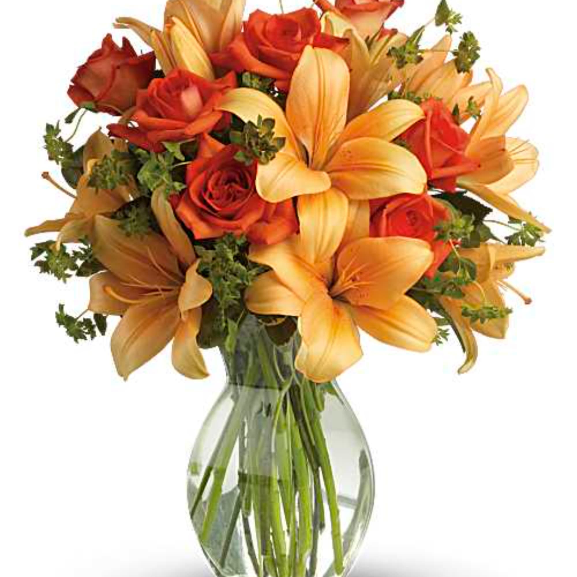 Orange roses and lilies arranged in a clear glass vase