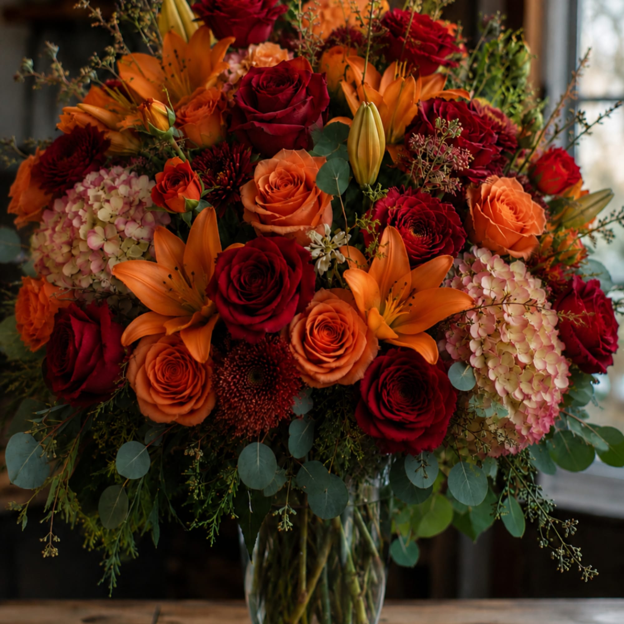 Bouquet of red and orange roses with lilies in a glass vase