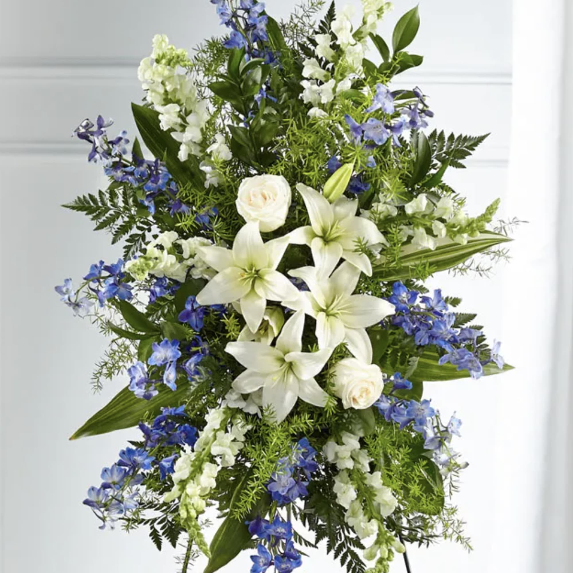 Tall standing floral spray with white lilies and blue flowers