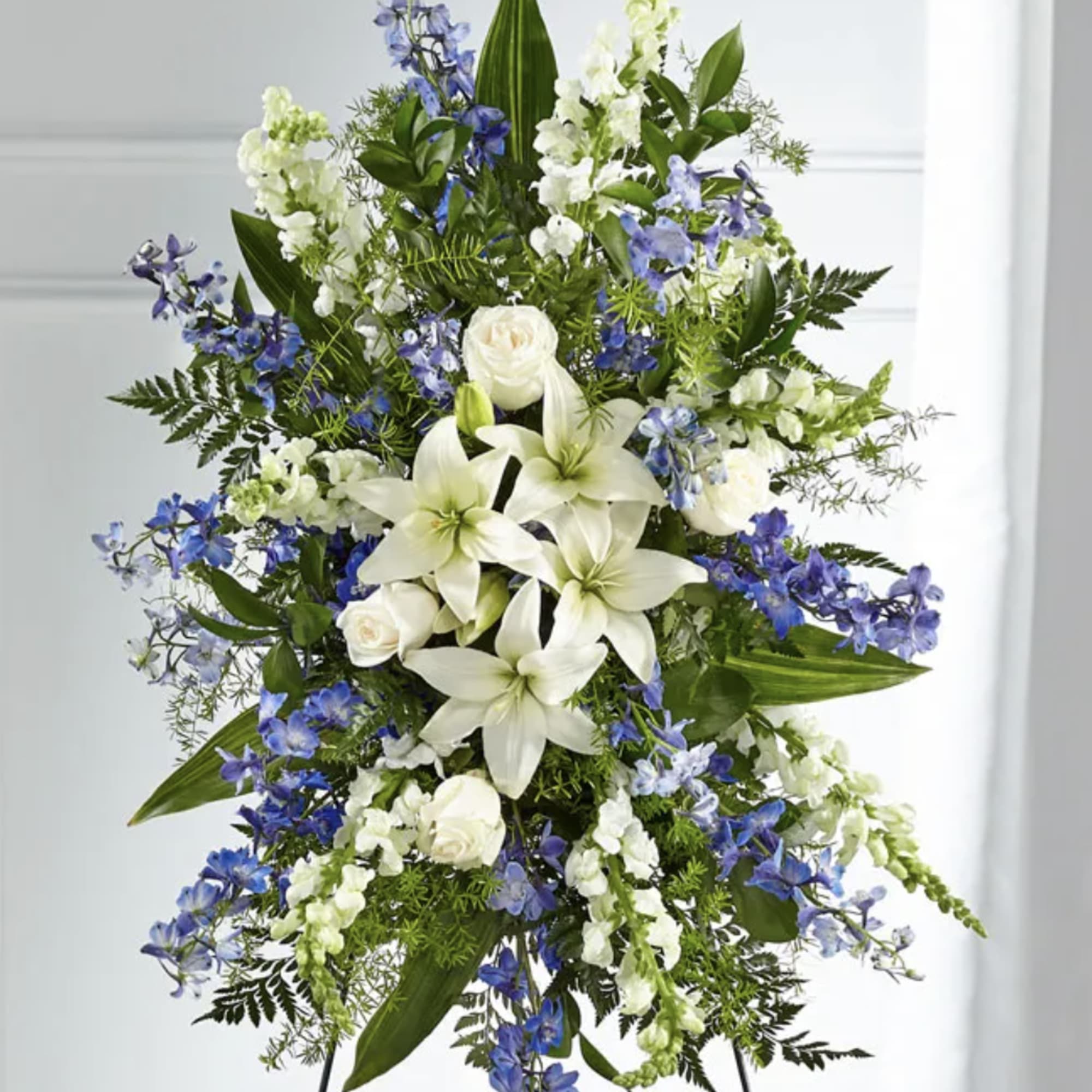 Tall white and blue floral standing spray on an easel