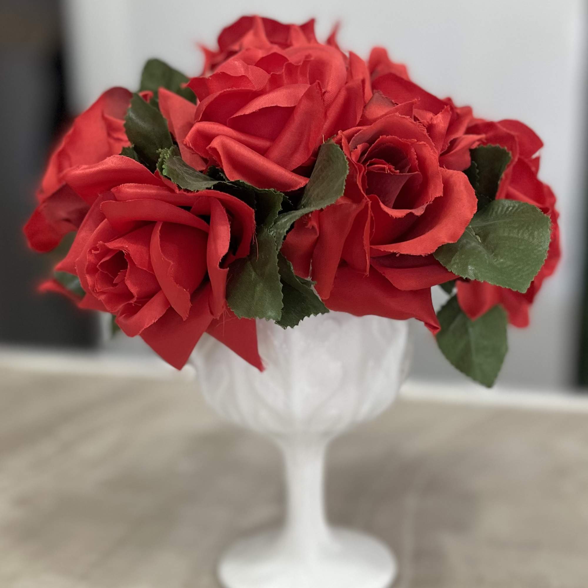 Red roses arranged in a white goblet vase