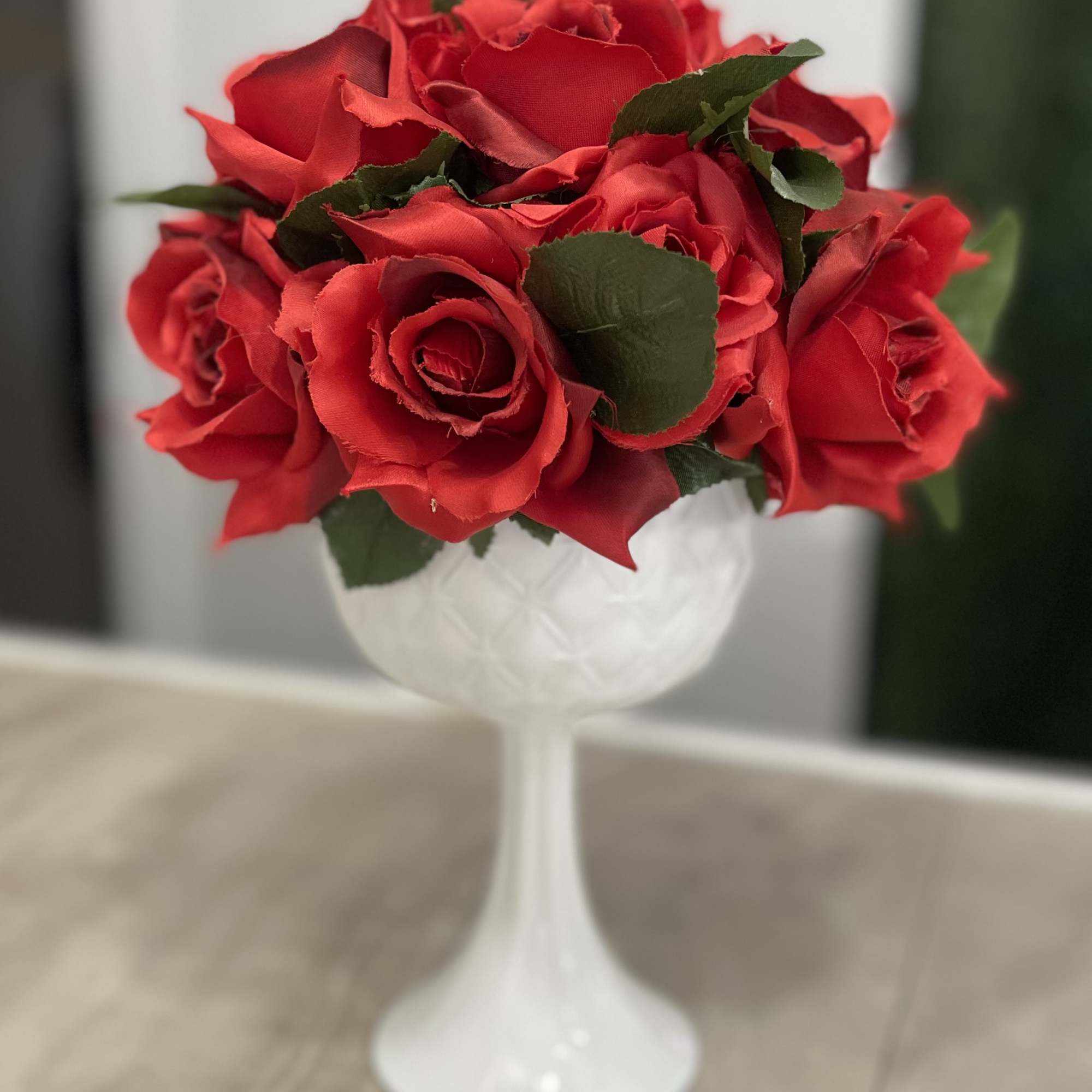 Red roses arranged in a white goblet vase