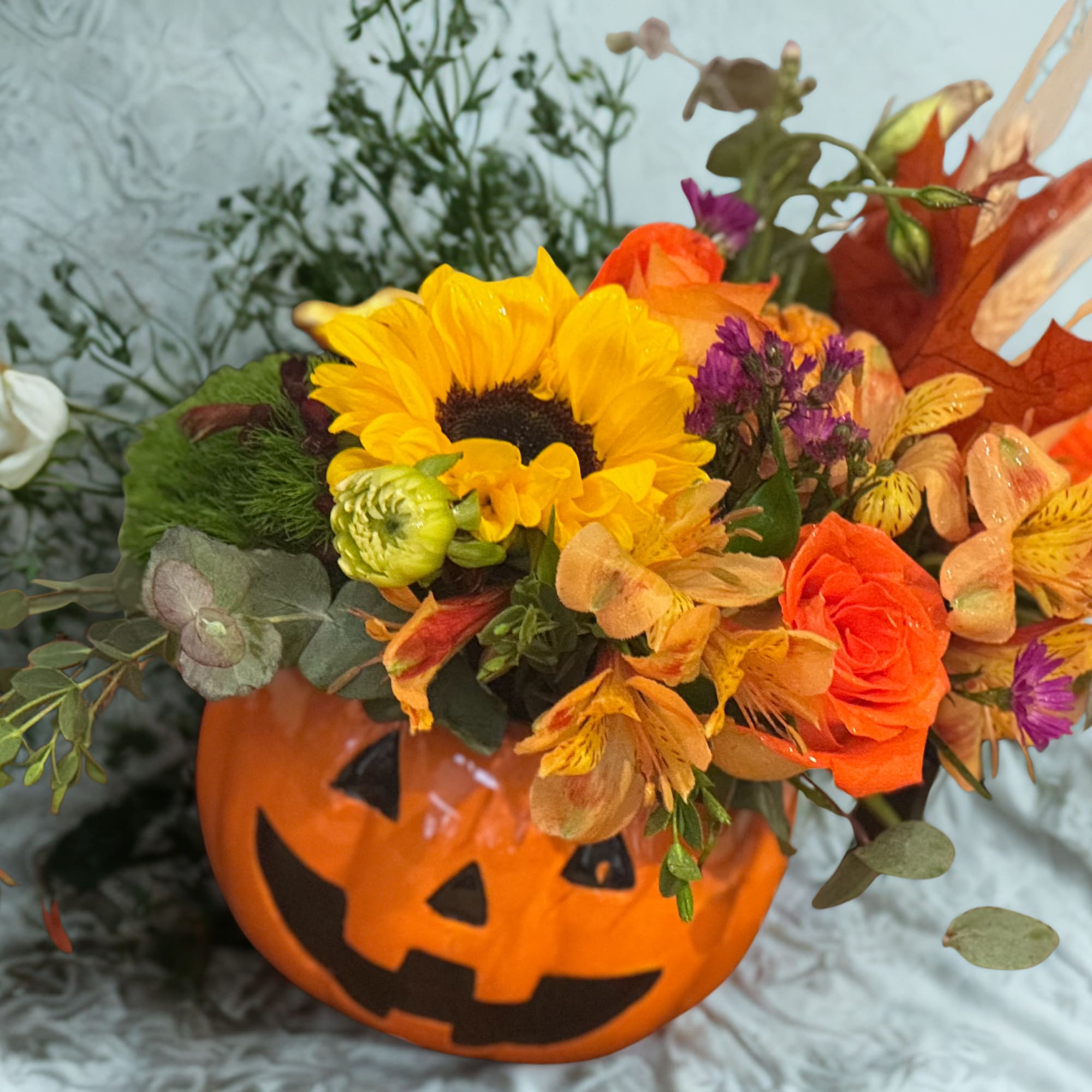 Fall flowers including sunflowers, filler flower, orange roses, alstroemeria, fall leaves, wheat