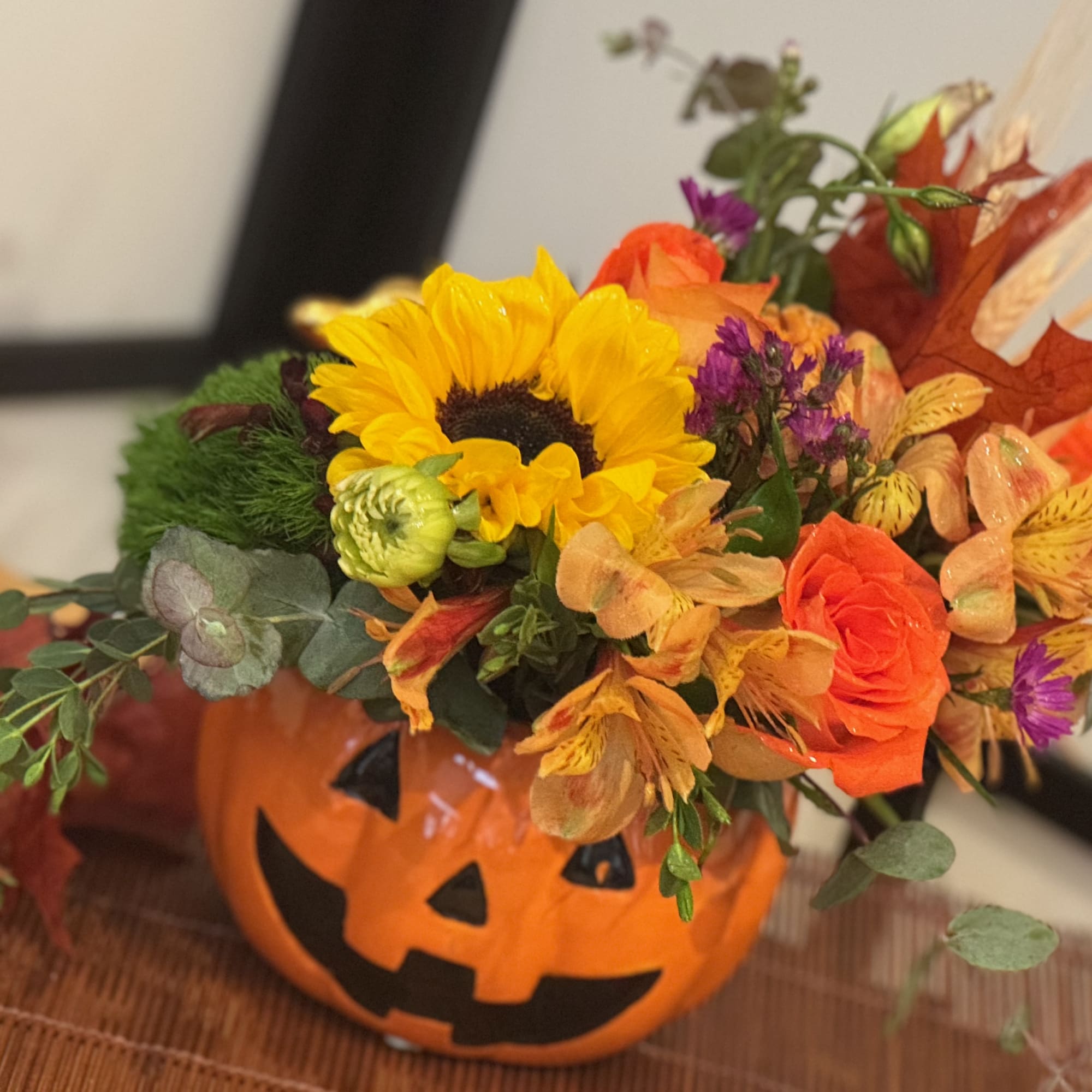 Fall flowers including sunflowers, filler flower, orange roses, alstroemeria, fall leaves, wheat