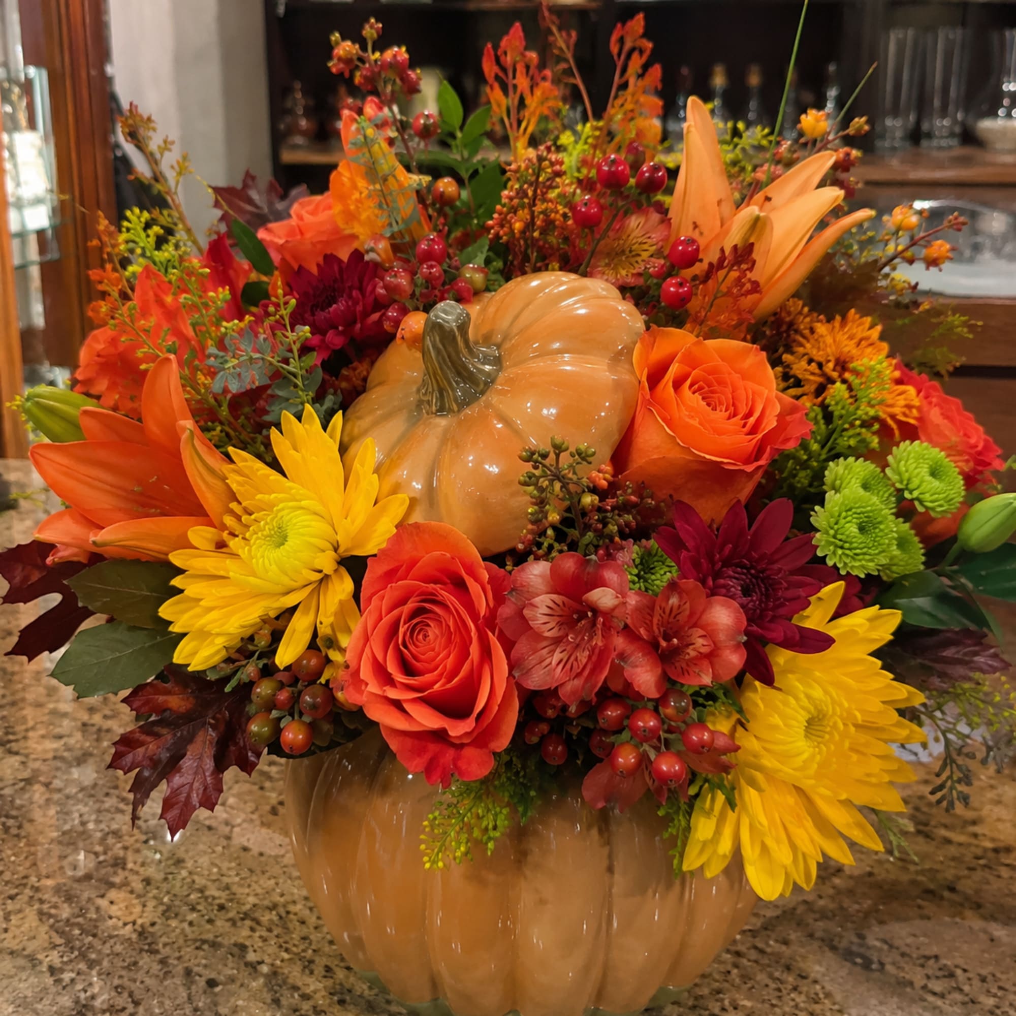 Glossy pumpkin-shaped ceramic vase at the center gives this fall flower arrangement