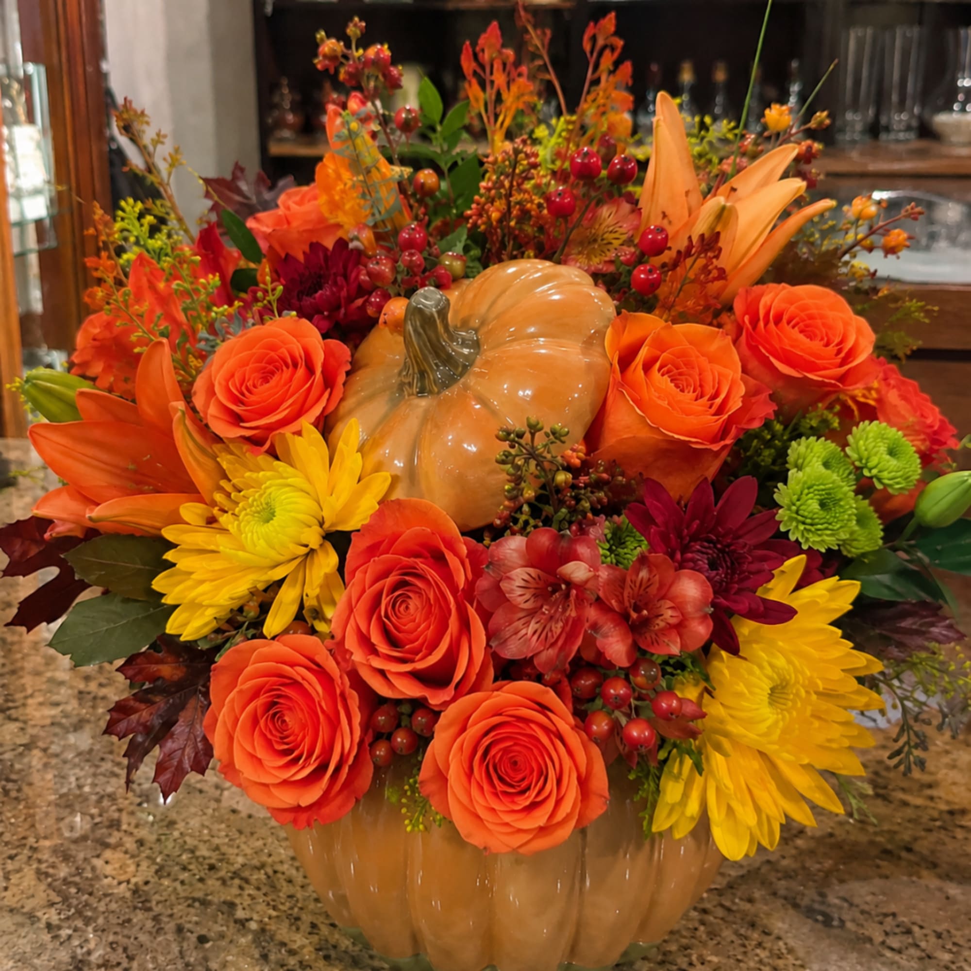 Orange and yellow floral arrangement in a pumpkin container