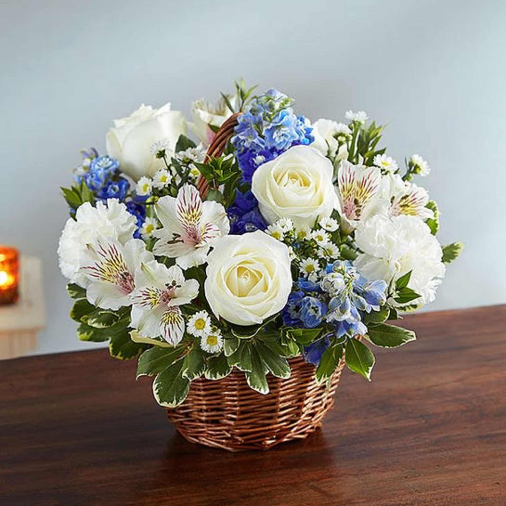 Basket arrangement of white roses, blue flowers, and white alstroemeria