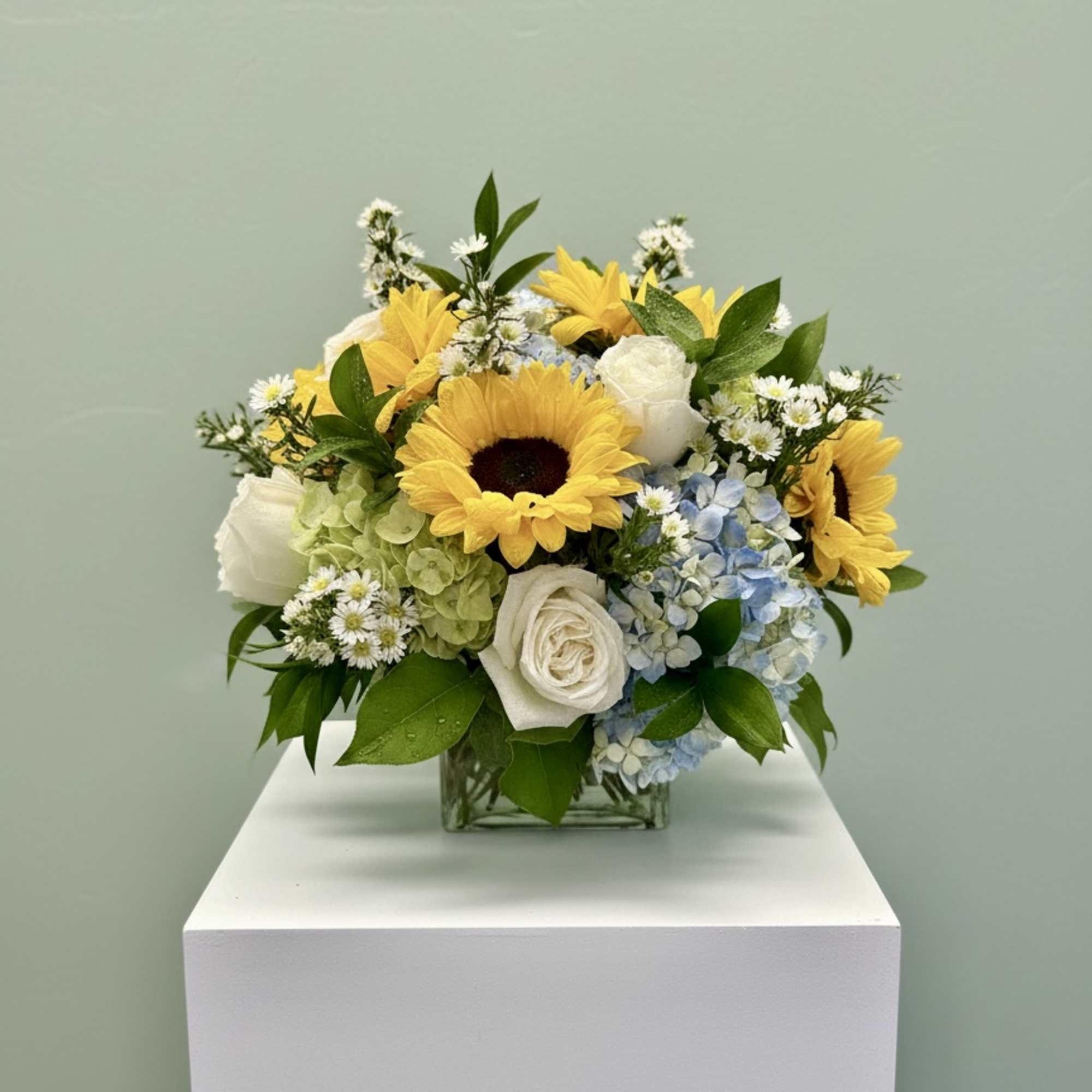 Yellow sunflowers and white roses in a square glass vase