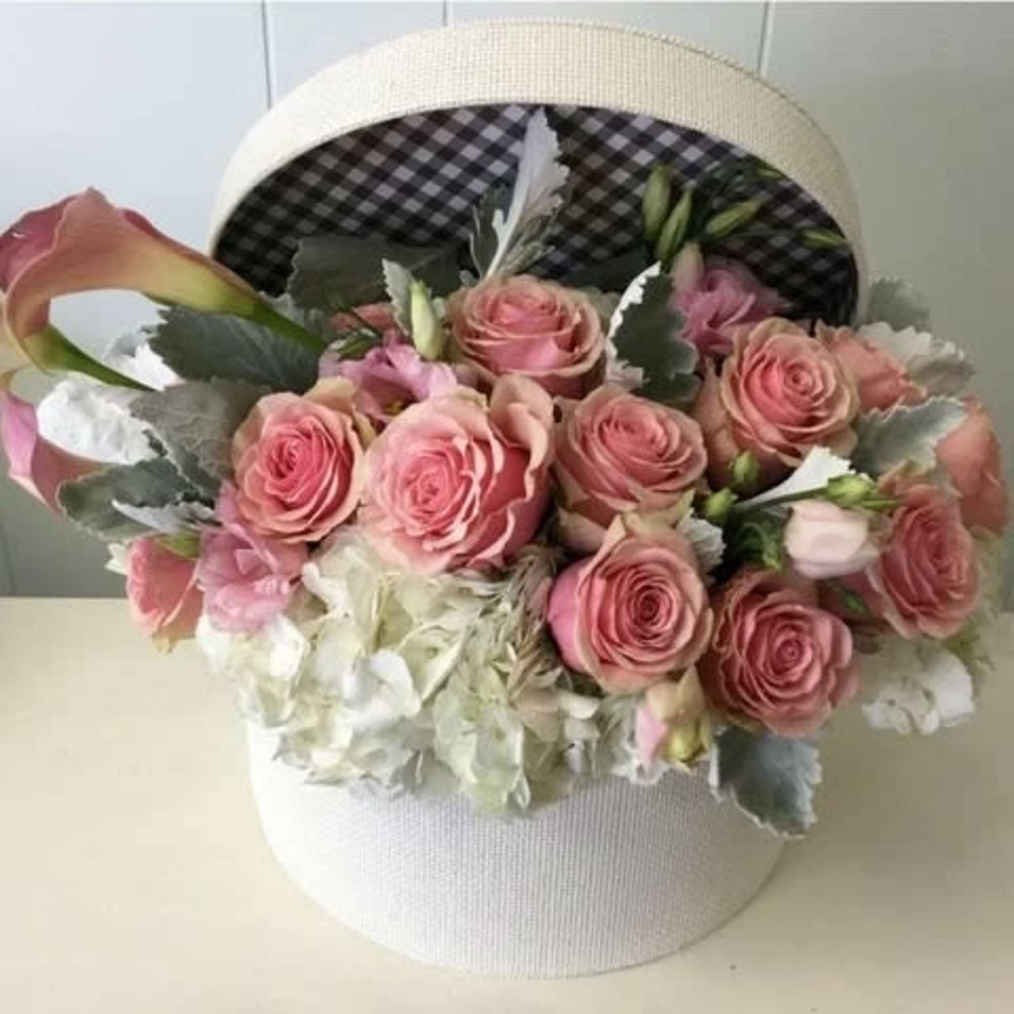 Pink roses and calla lilies arranged in a white hatbox