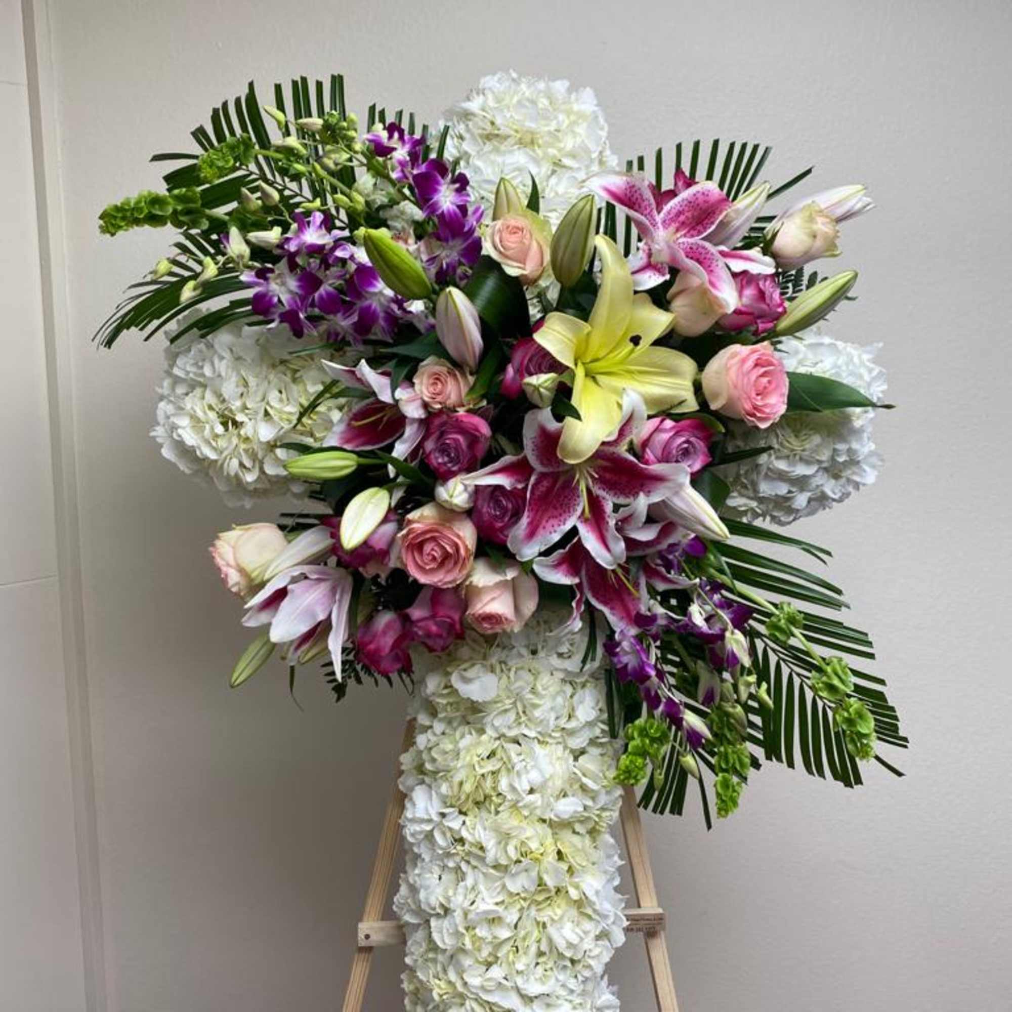 Large floral cross with white hydrangeas, pink roses, and lilies