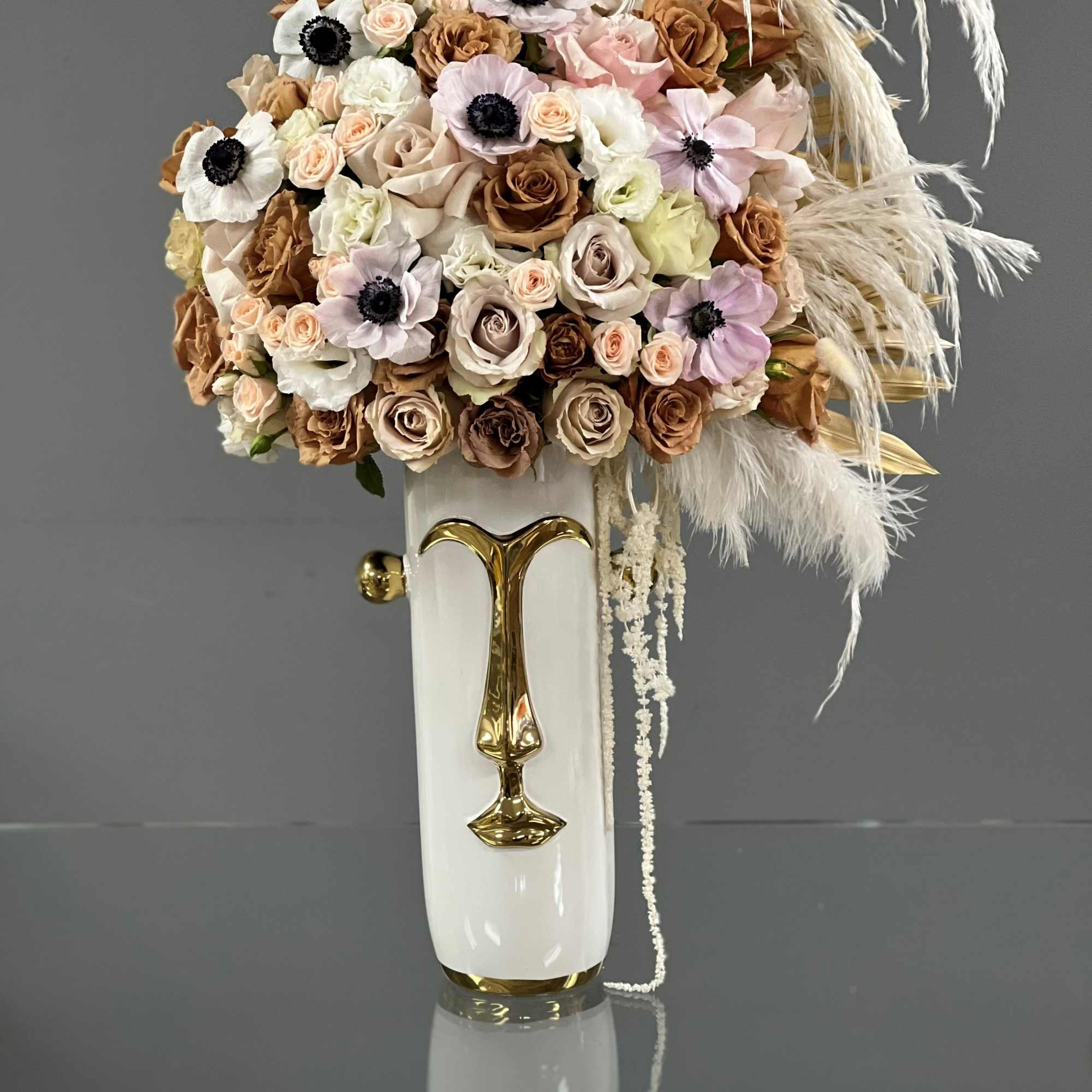 Bouquet of blush and tan flowers in a white vase with gold accents