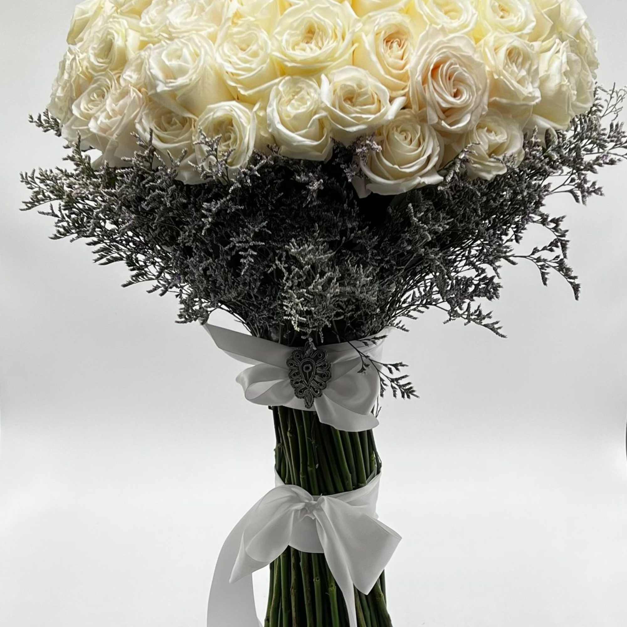 Bouquet of white roses with dark filler and white ribbon