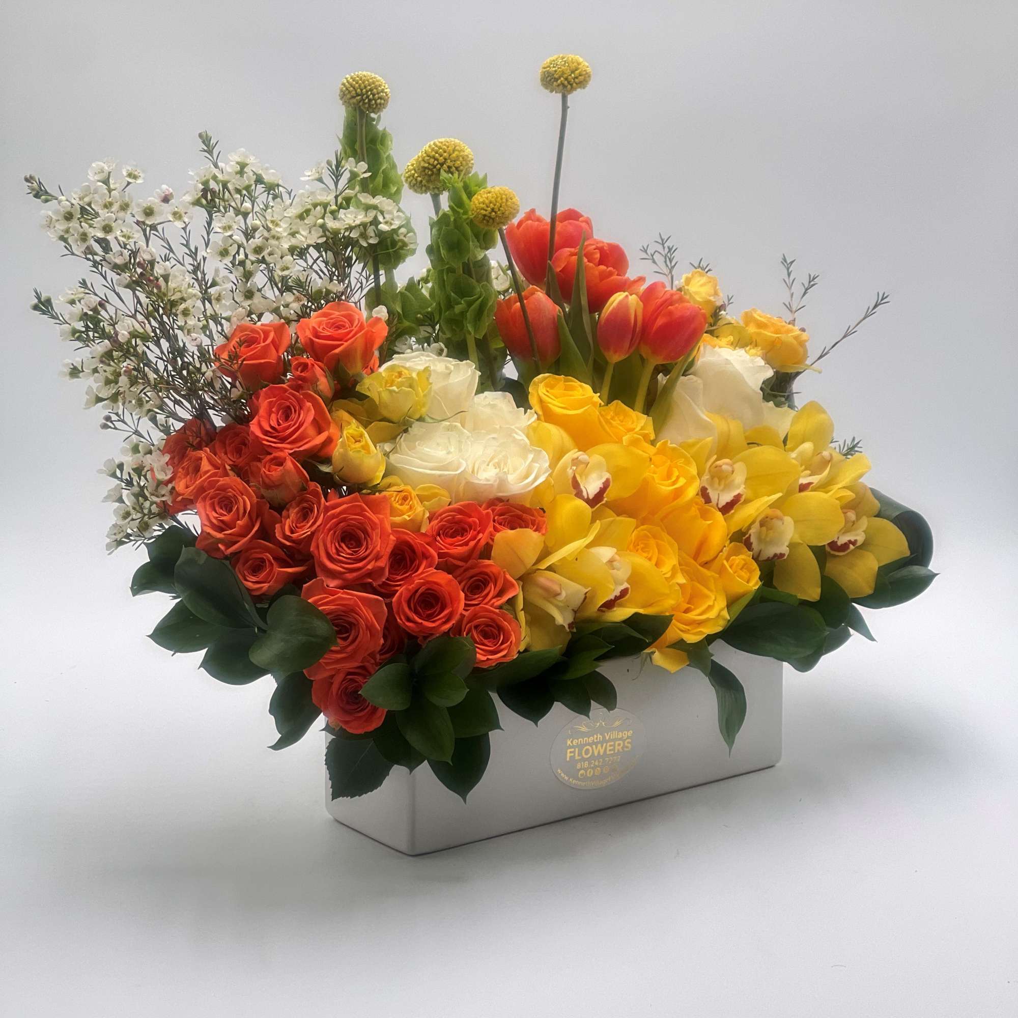 Mixed bouquet of roses, tulips, and orchids in a rectangular box