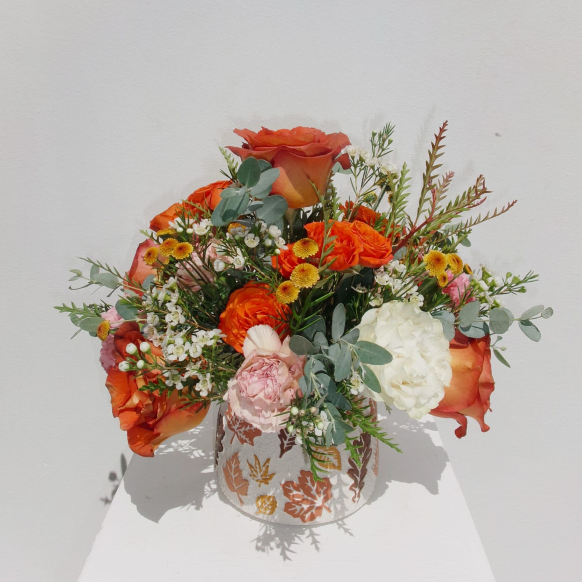 Orange and white floral arrangement in a patterned vase