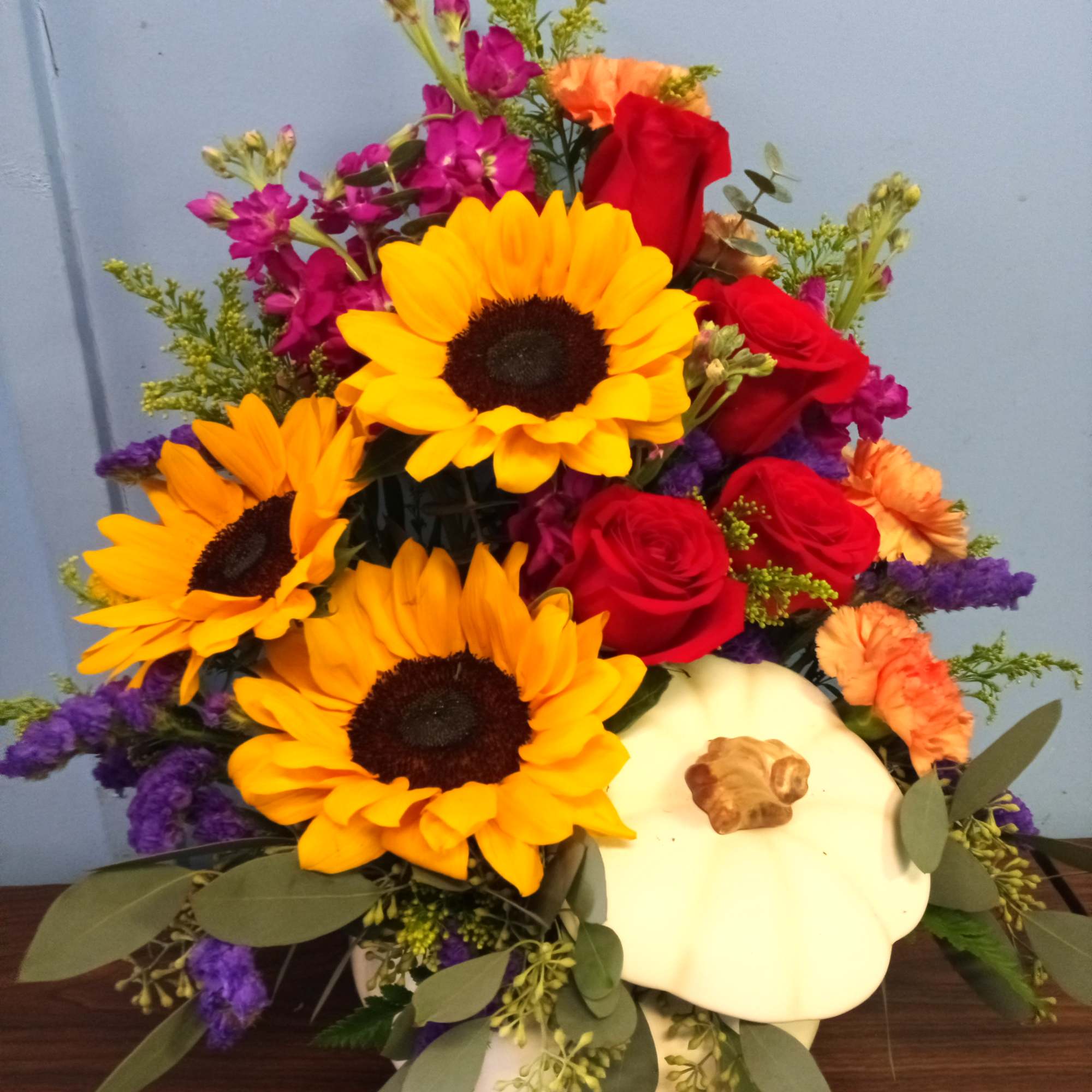 Mixed bouquet with sunflowers, red roses, and a white pumpkin container