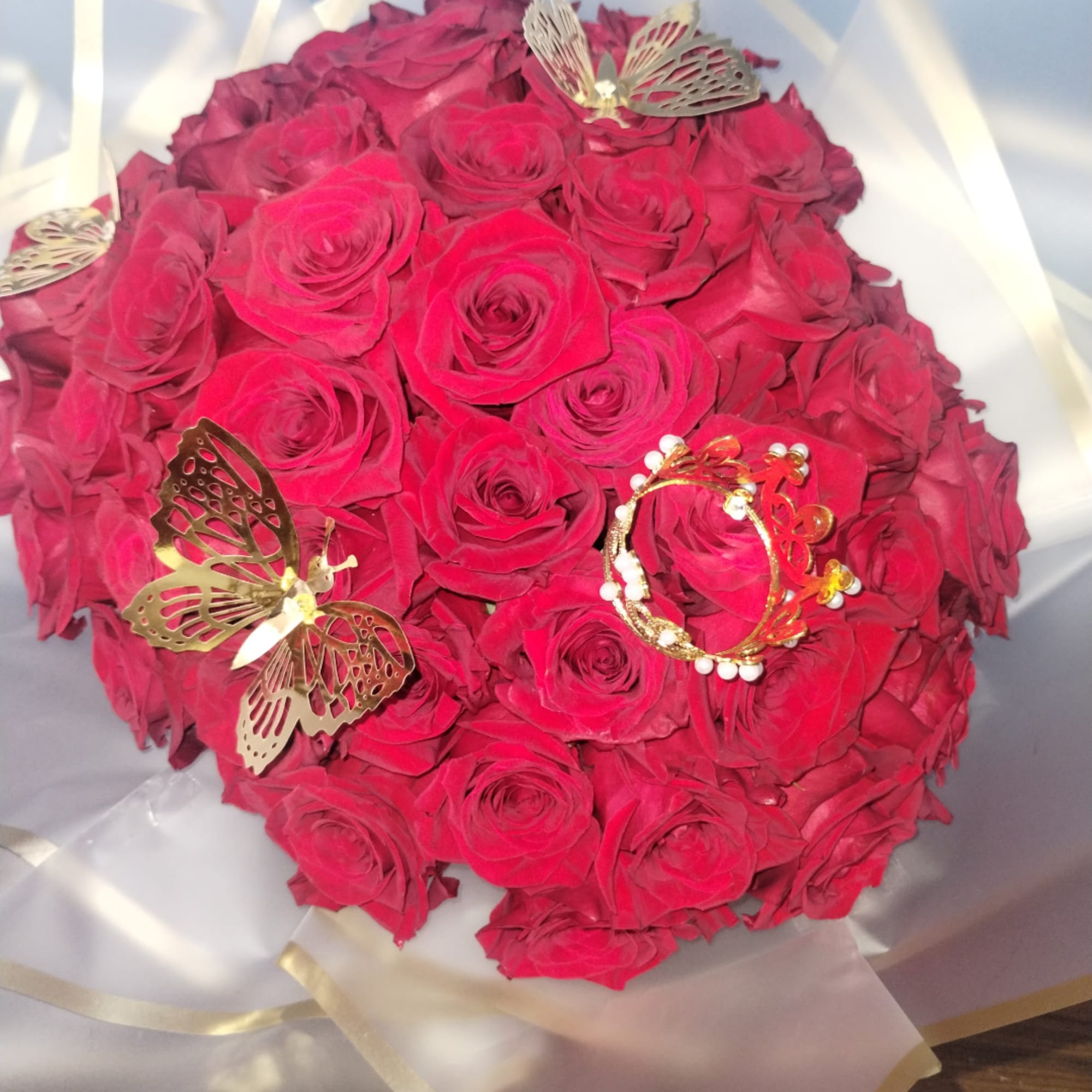 Bouquet of red roses wrapped in translucent paper with butterfly decorations