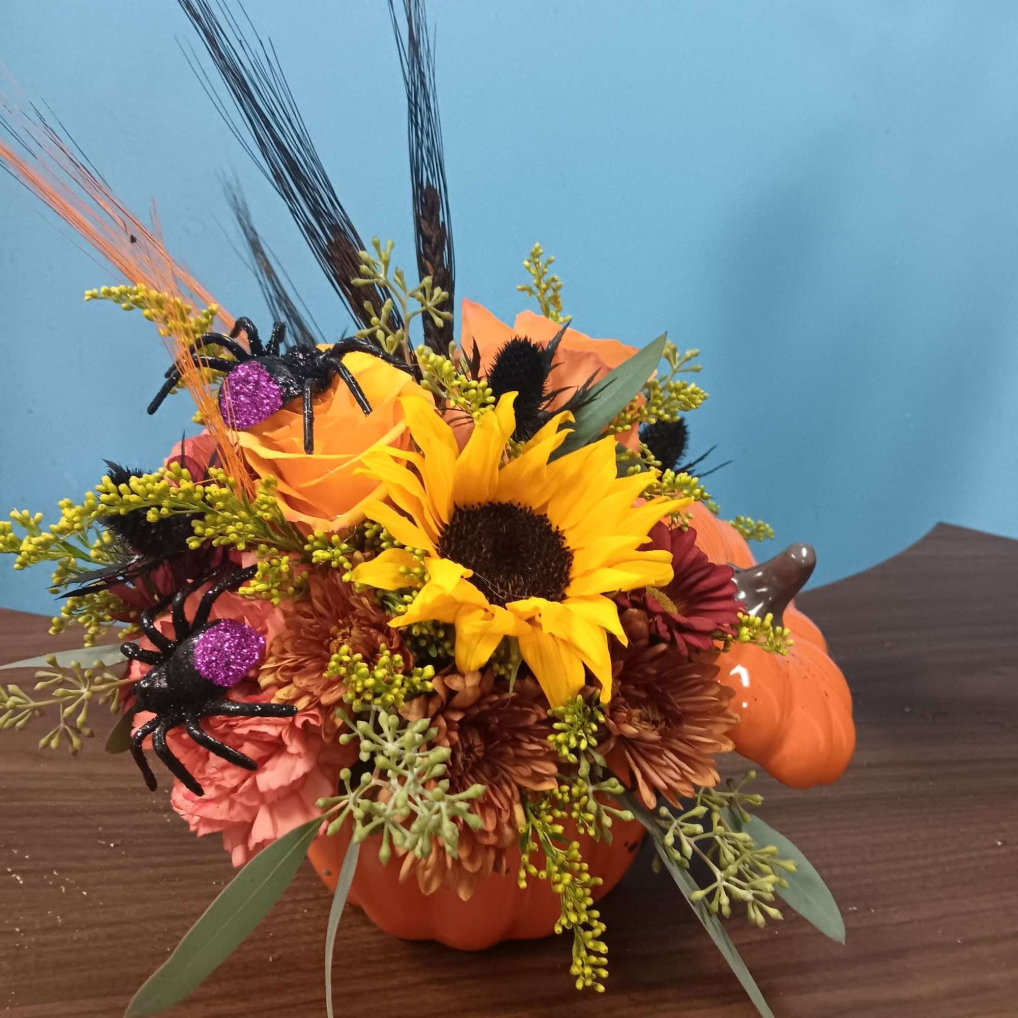Halloween floral arrangement in a pumpkin container with spiders and sunflowers