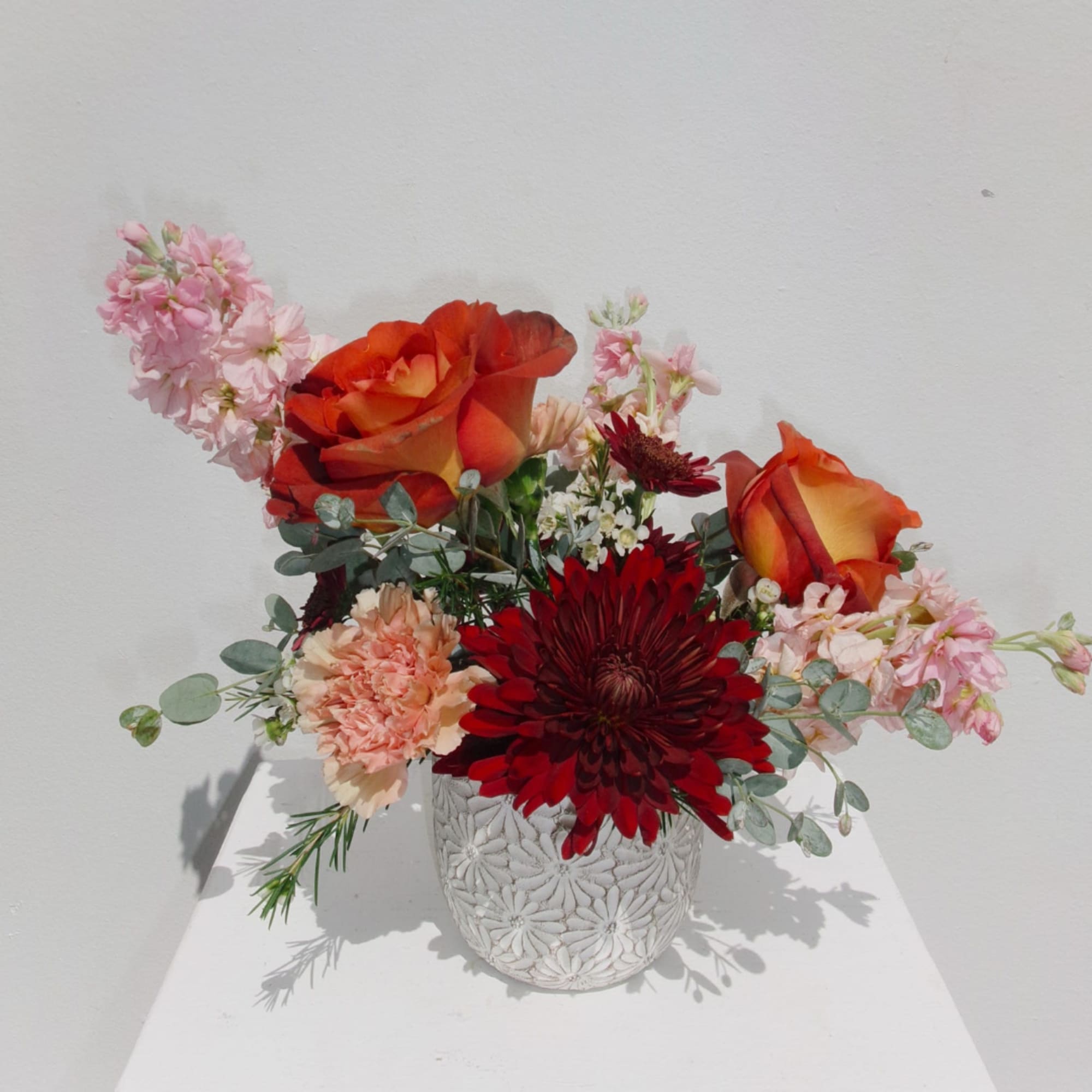 Mixed bouquet with orange roses and red chrysanthemums in a white vase