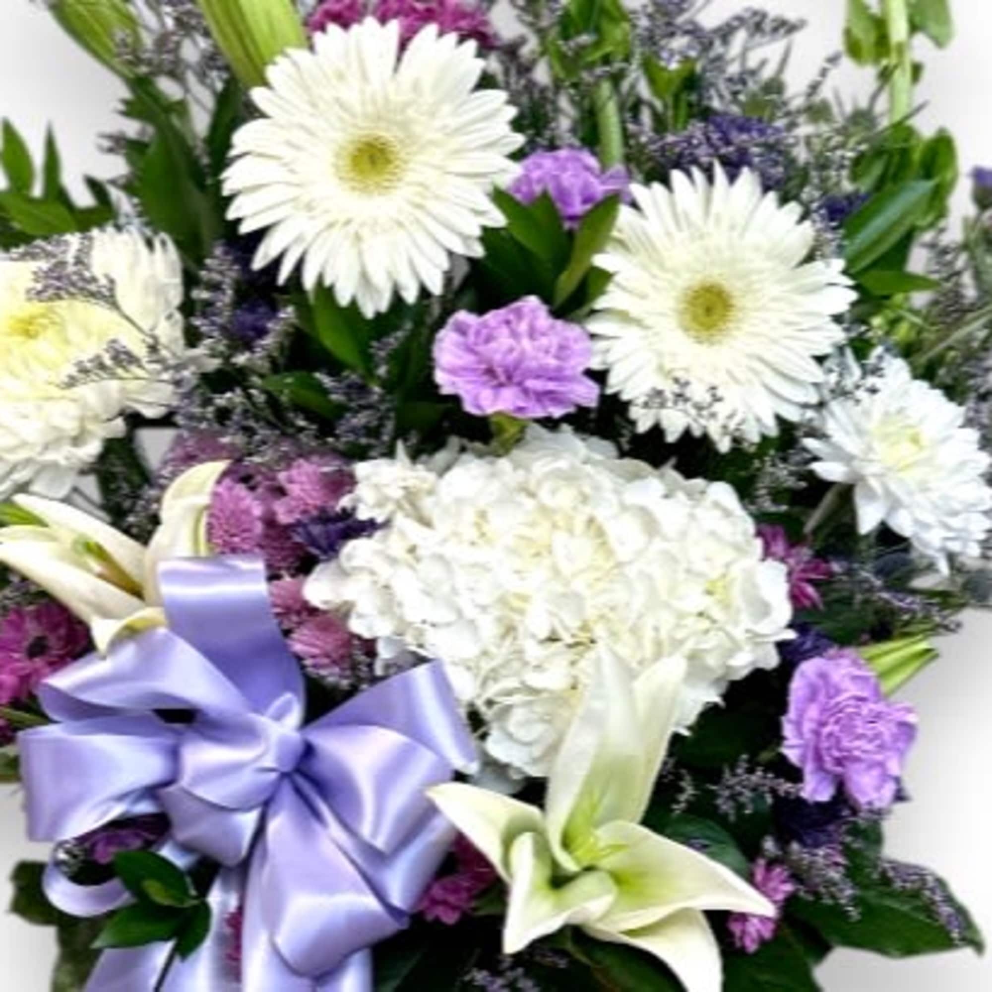 White and purple floral arrangement with a lavender ribbon bow