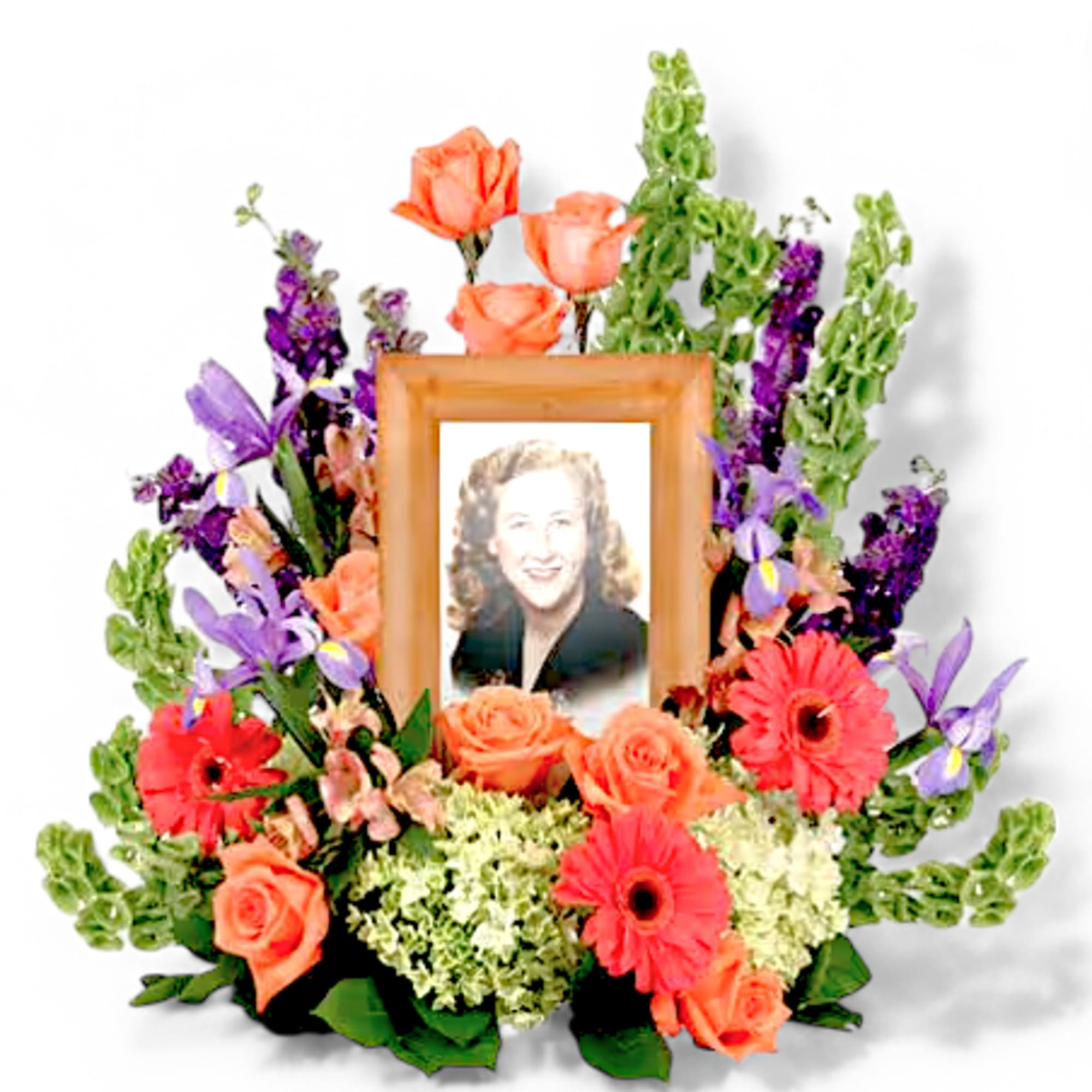 Framed portrait surrounded by orange roses, gerbera daisies, and purple flowers