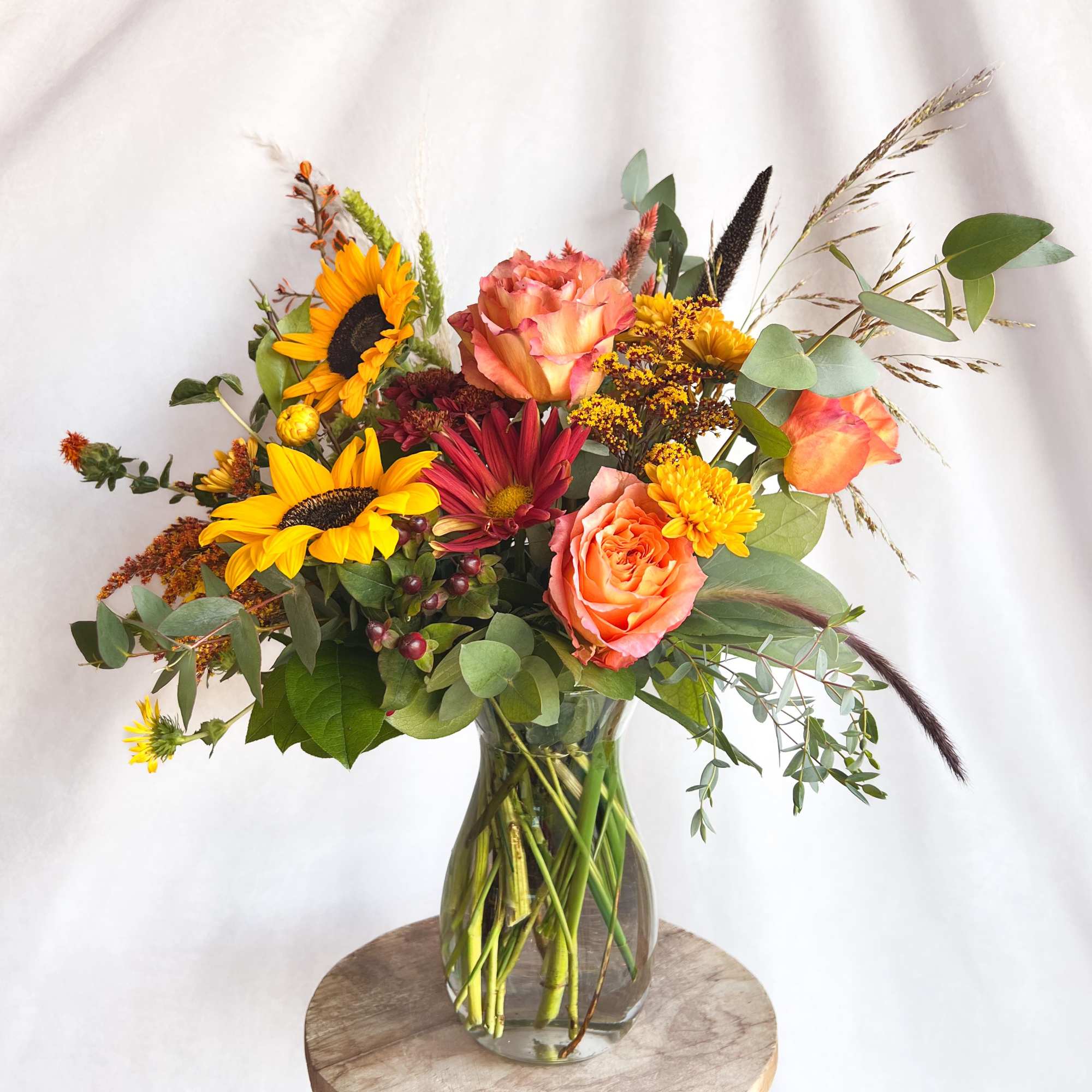 Mixed bouquet in a clear glass vase with sunflowers and peach roses
