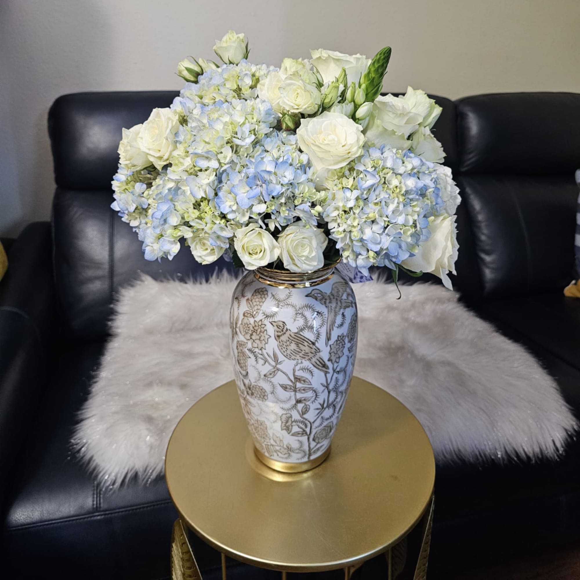 White roses and pale blue hydrangeas in a decorative vase