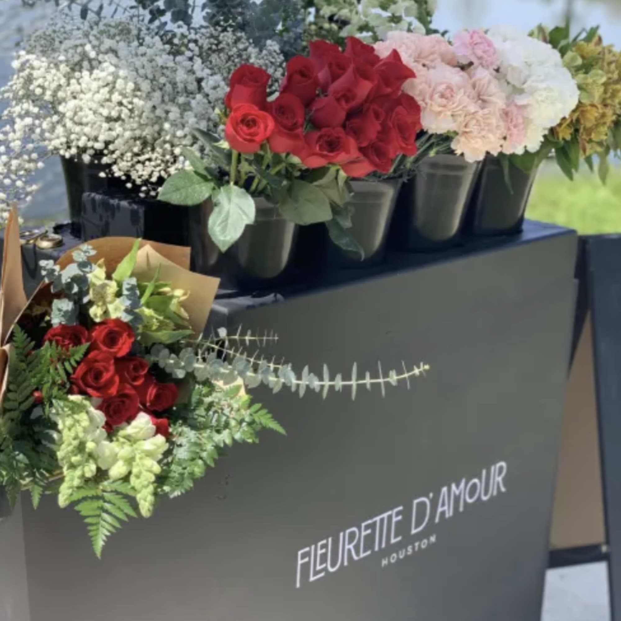 Bouquets of red and blush roses in black buckets on a display table