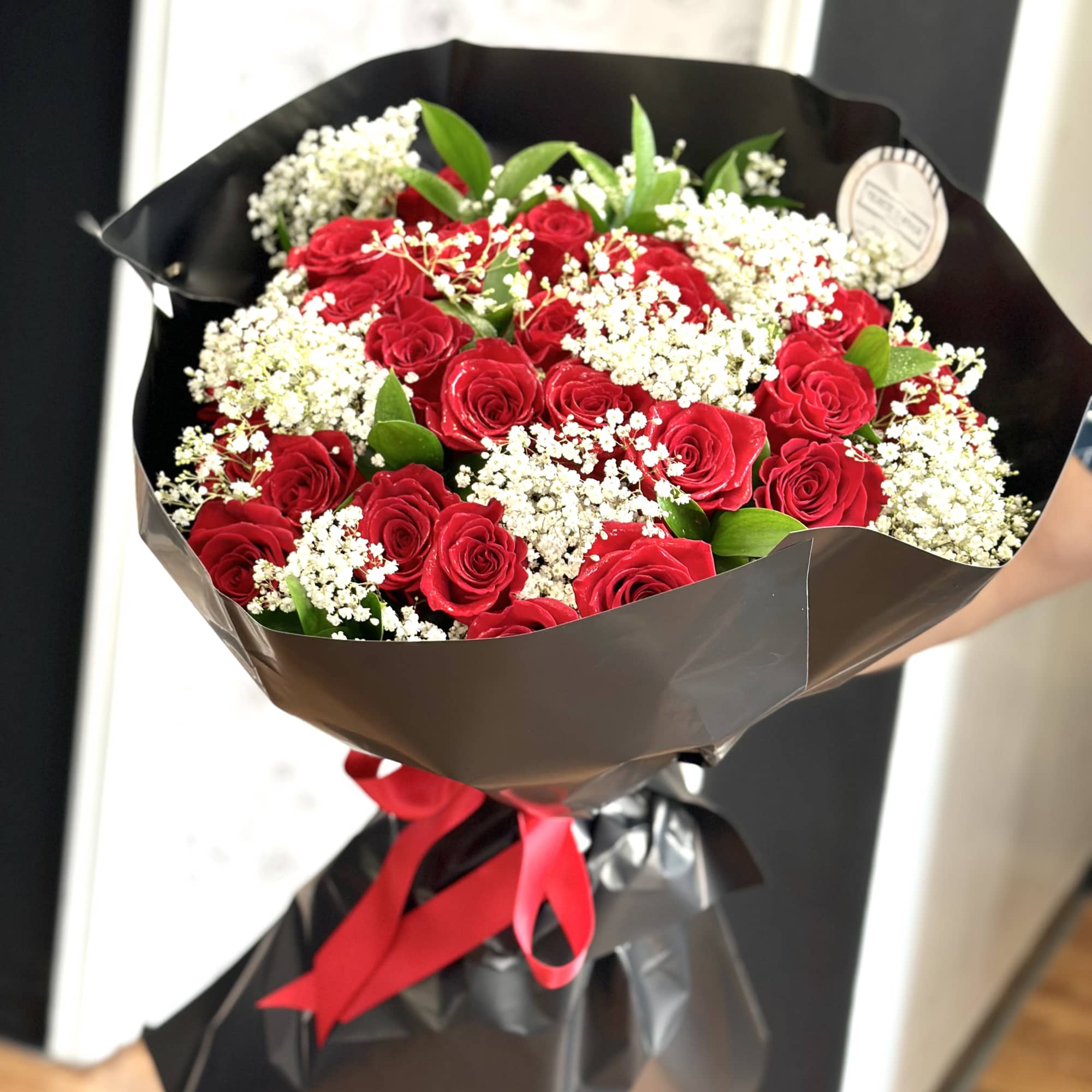 Bouquet of red roses with white baby's breath in black wrap