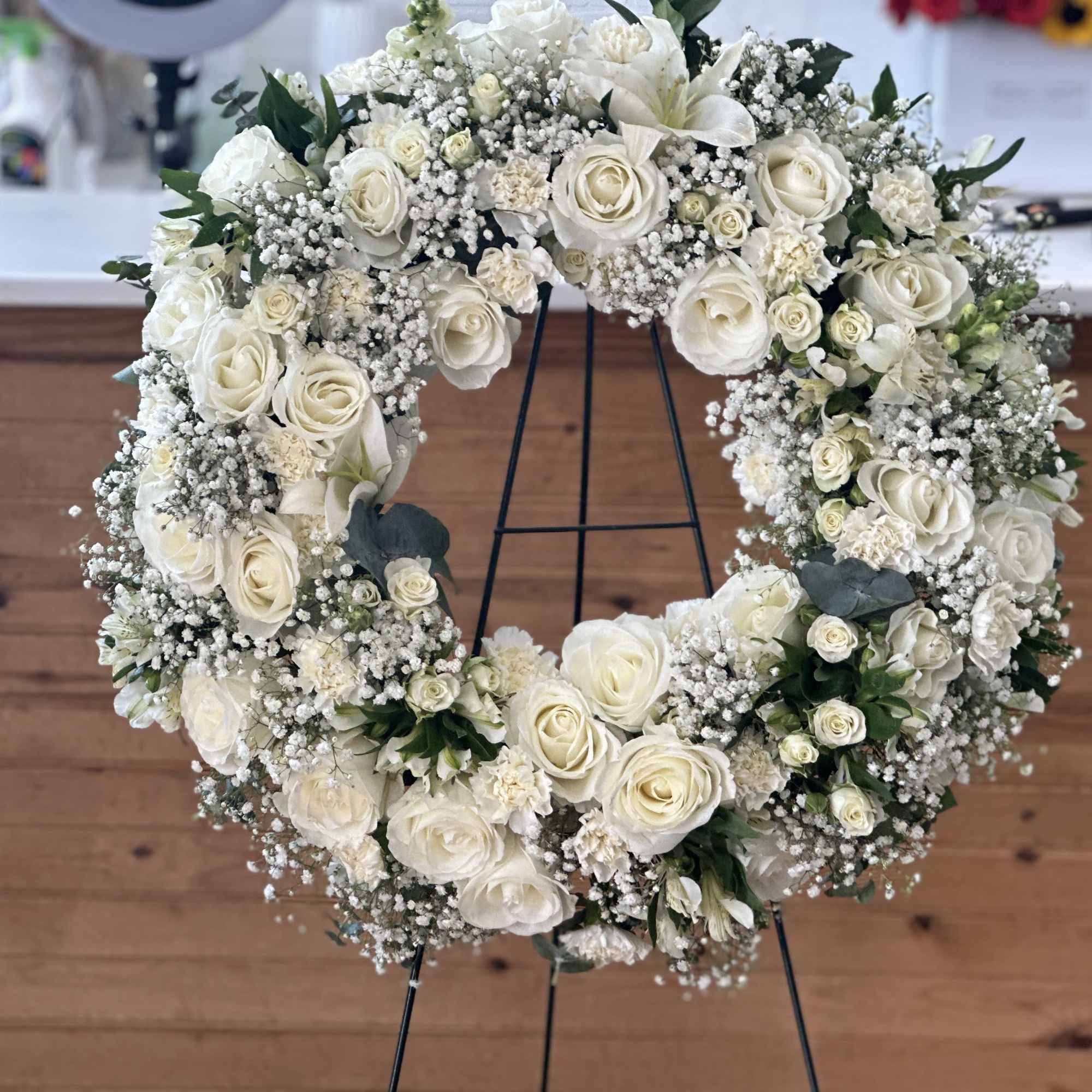 White rose wreath on a black stand