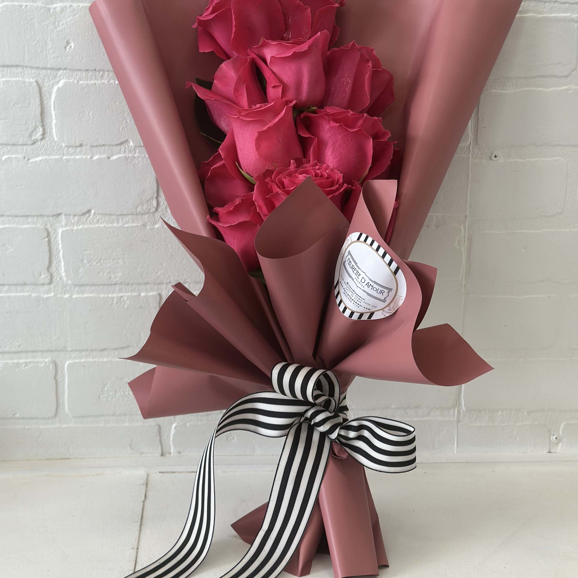 Bouquet of hot pink roses wrapped in dusty pink paper with a striped ribbon