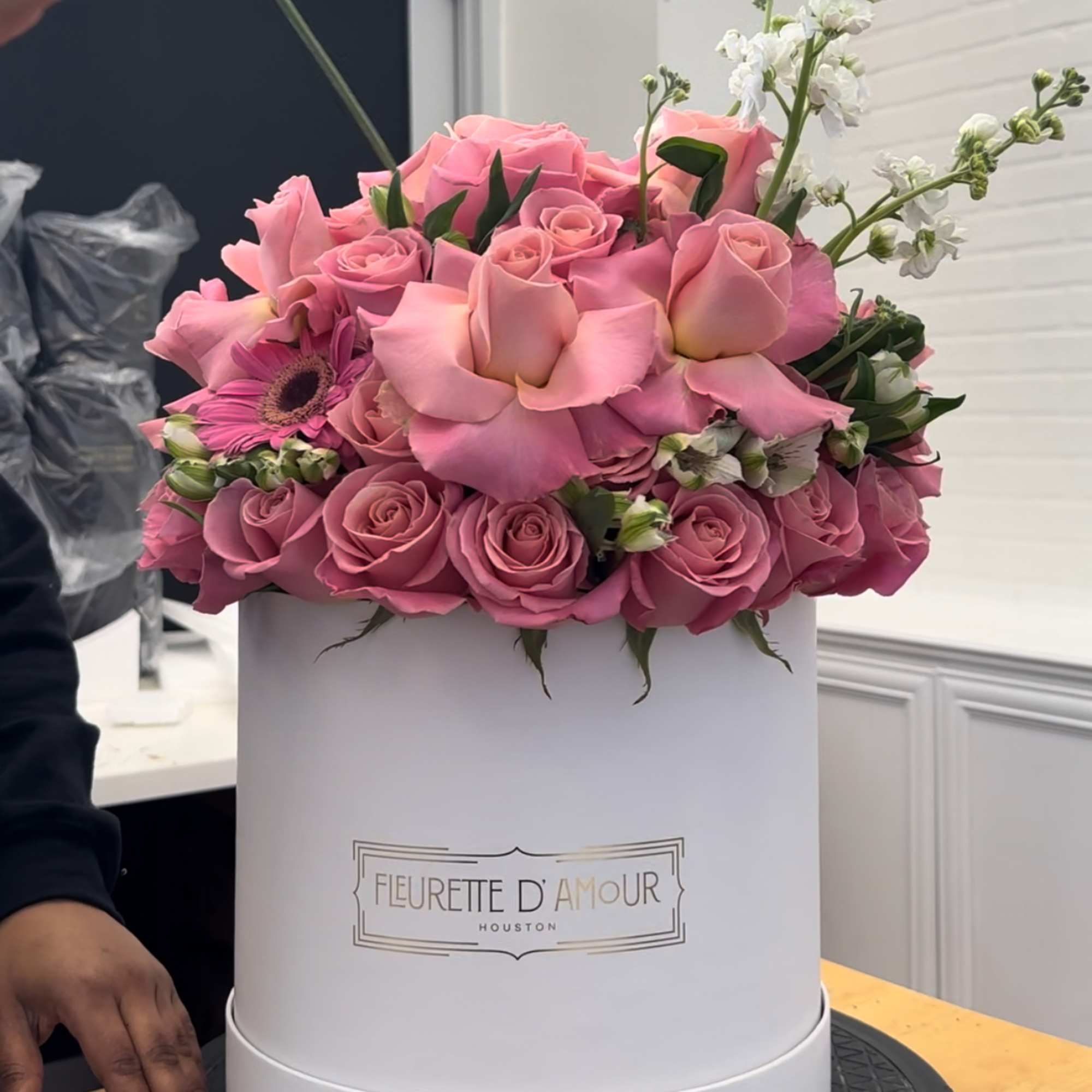 Pink roses and a pink gerbera daisy arranged in a white hat box