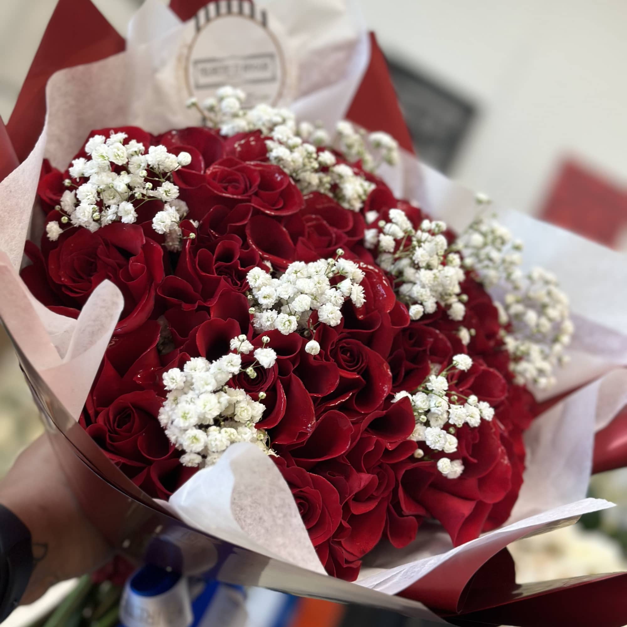 Bouquet of red roses with white baby's breath in pink and red wrap