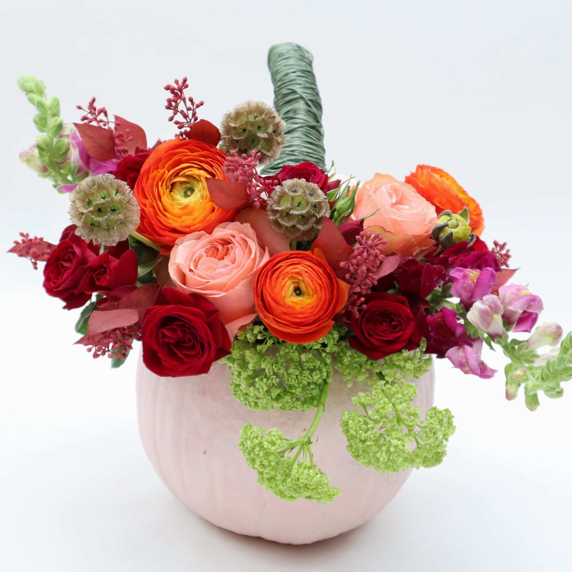 Mixed bouquet of red, pink, and orange flowers in a pale pink vase, photo 5 of 5