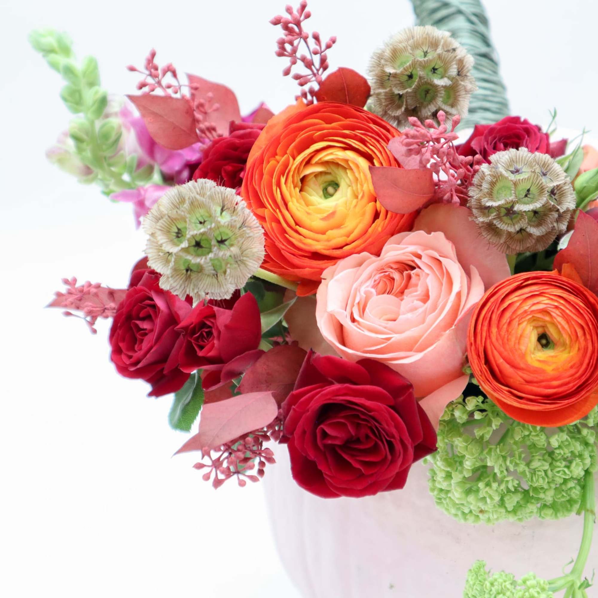 Mixed bouquet of roses and ranunculus in a white vase