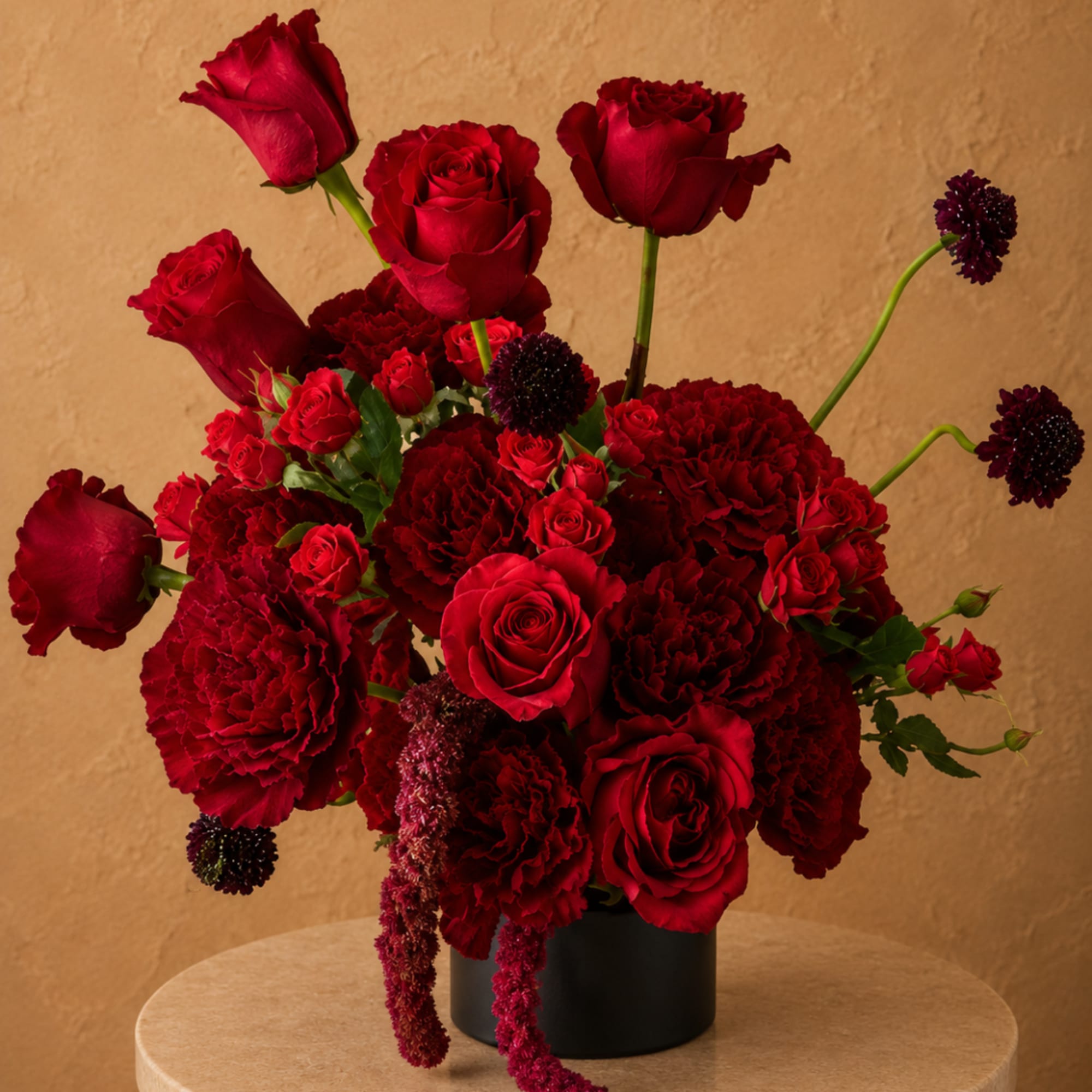 Red roses and carnations arranged in a black vase