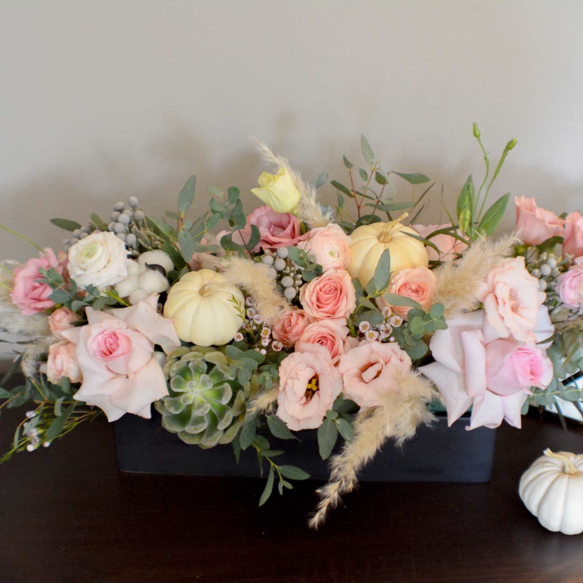Low floral centerpiece with pink and cream roses in a black container