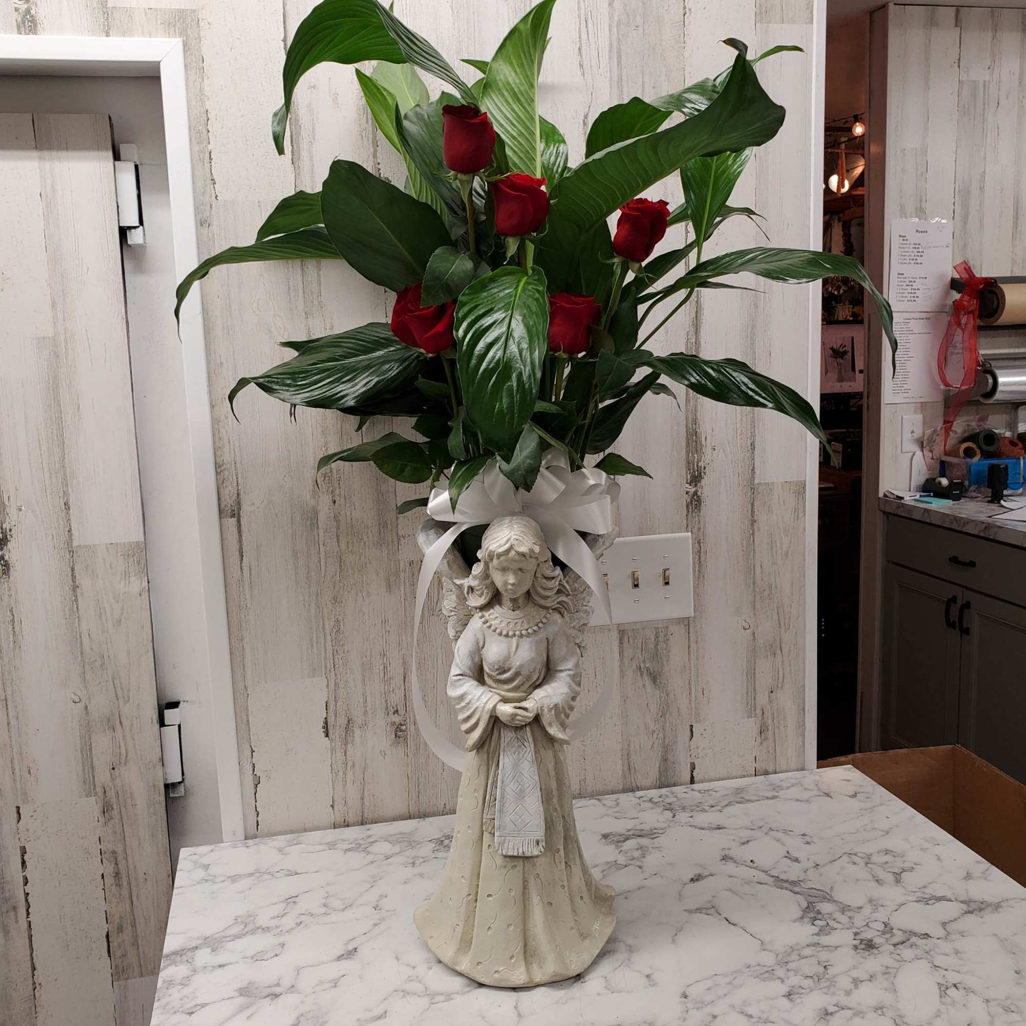 Tall arrangement of red roses in a decorative angel vase
