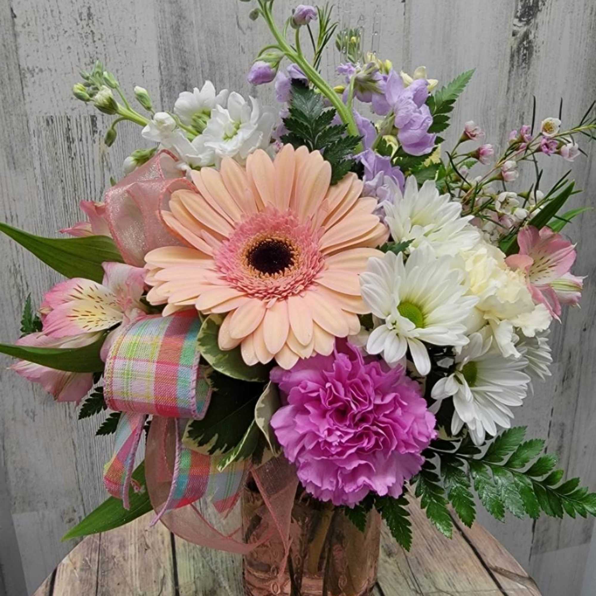 Pastel bouquet with gerbera daisies, carnations, and daisies in a glass vase