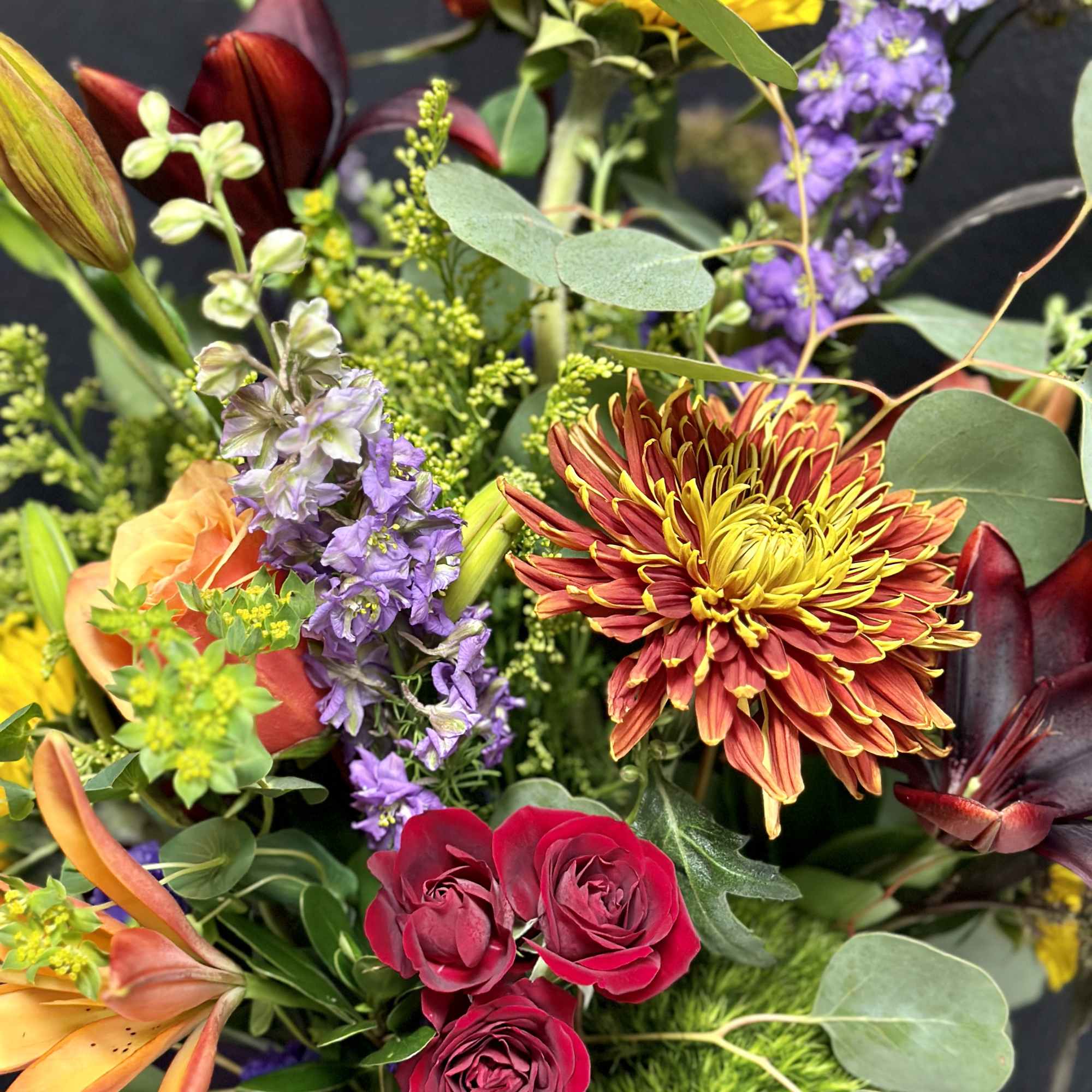 Mixed bouquet with red roses, orange lilies, yellow chrysanthemum, and purple flowers